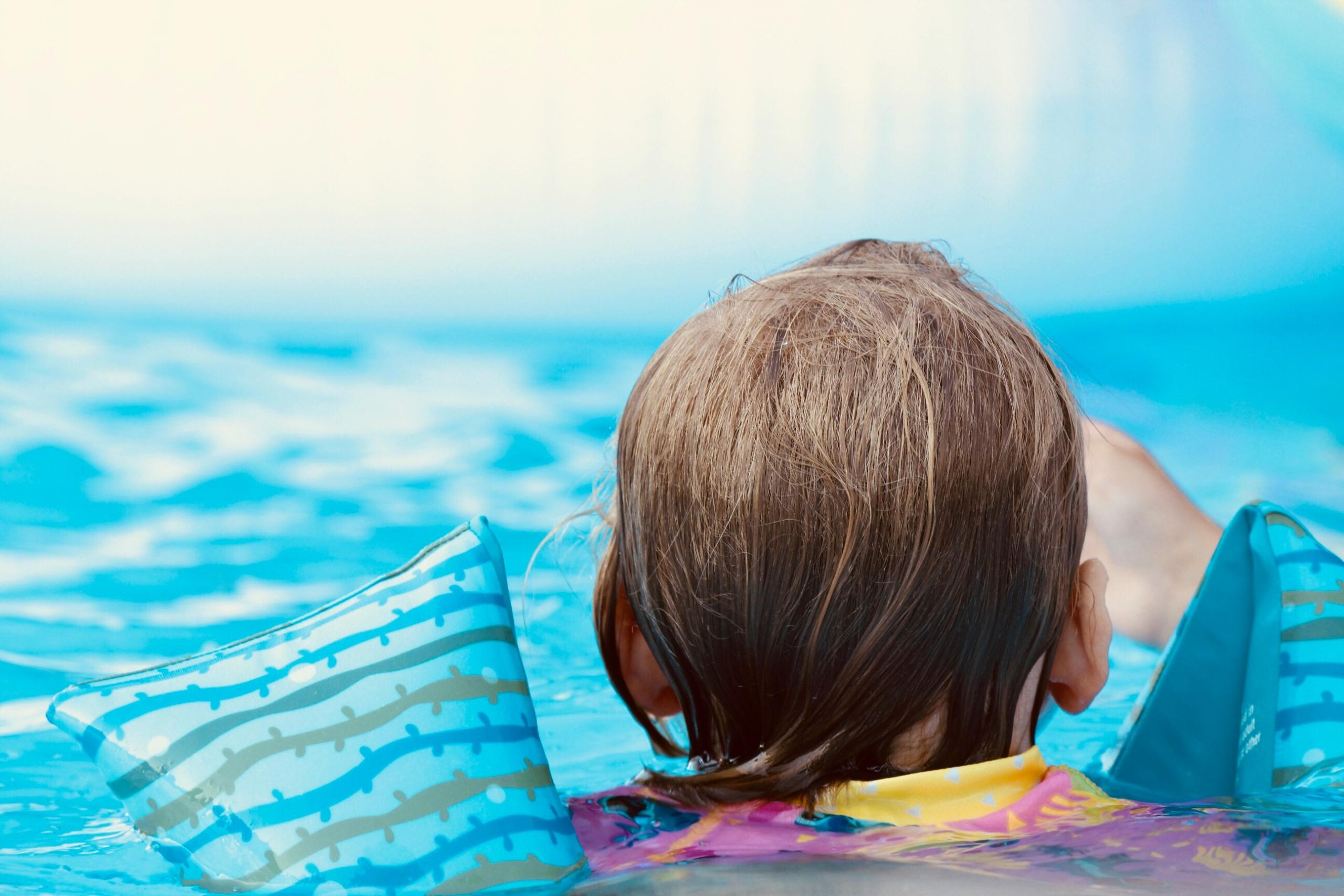 close up of child in pool wearing inflatable armbands