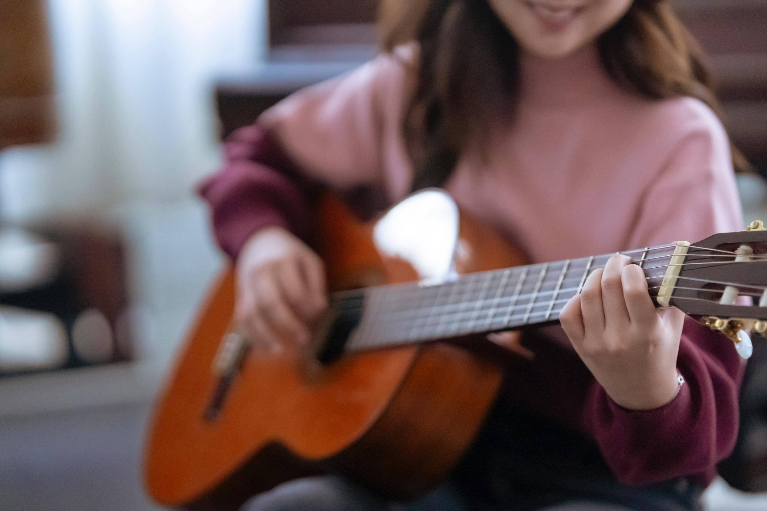 smiling woman playing the acoustic guitar