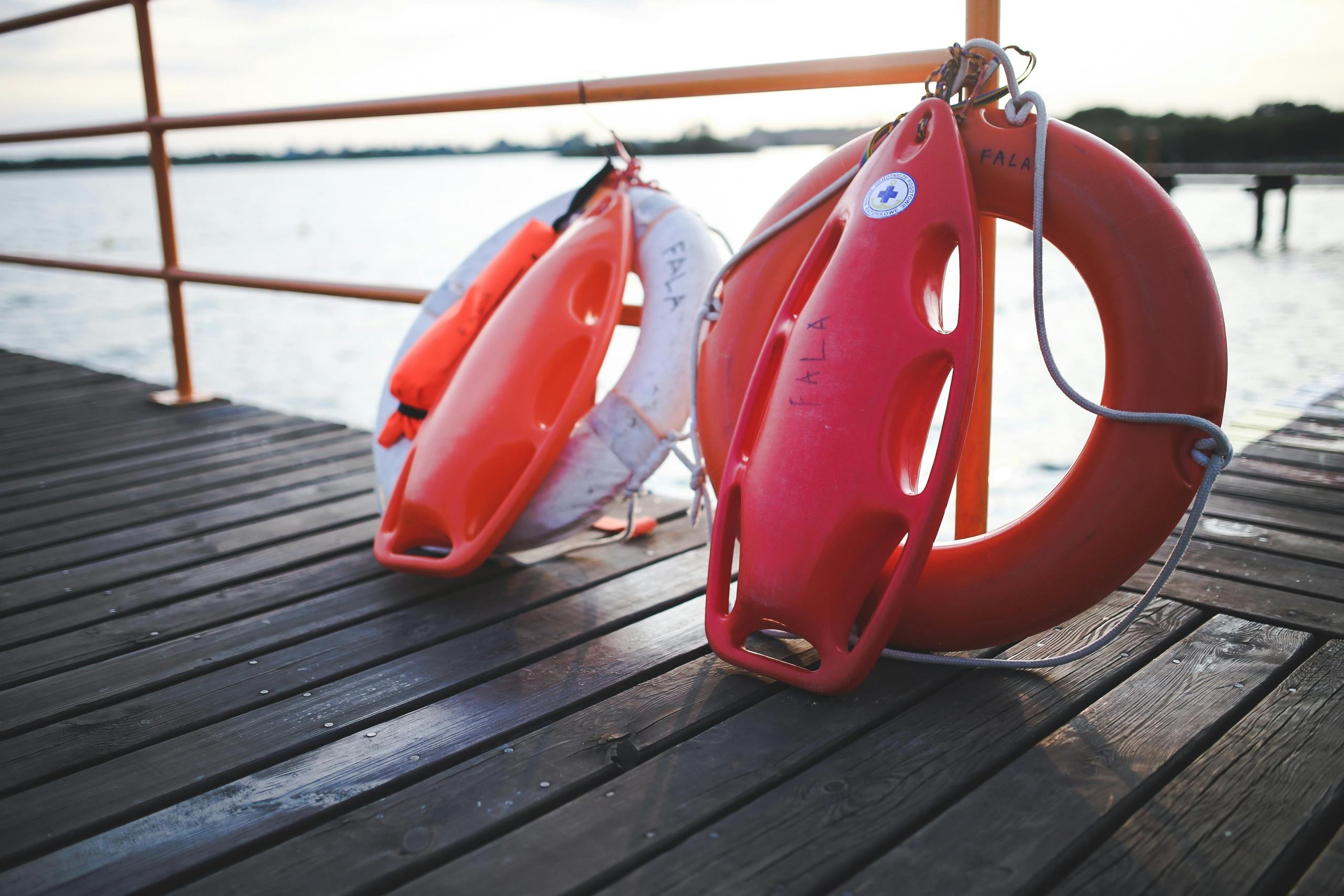 rescue cans and tubes placed upright against poles of a jetty