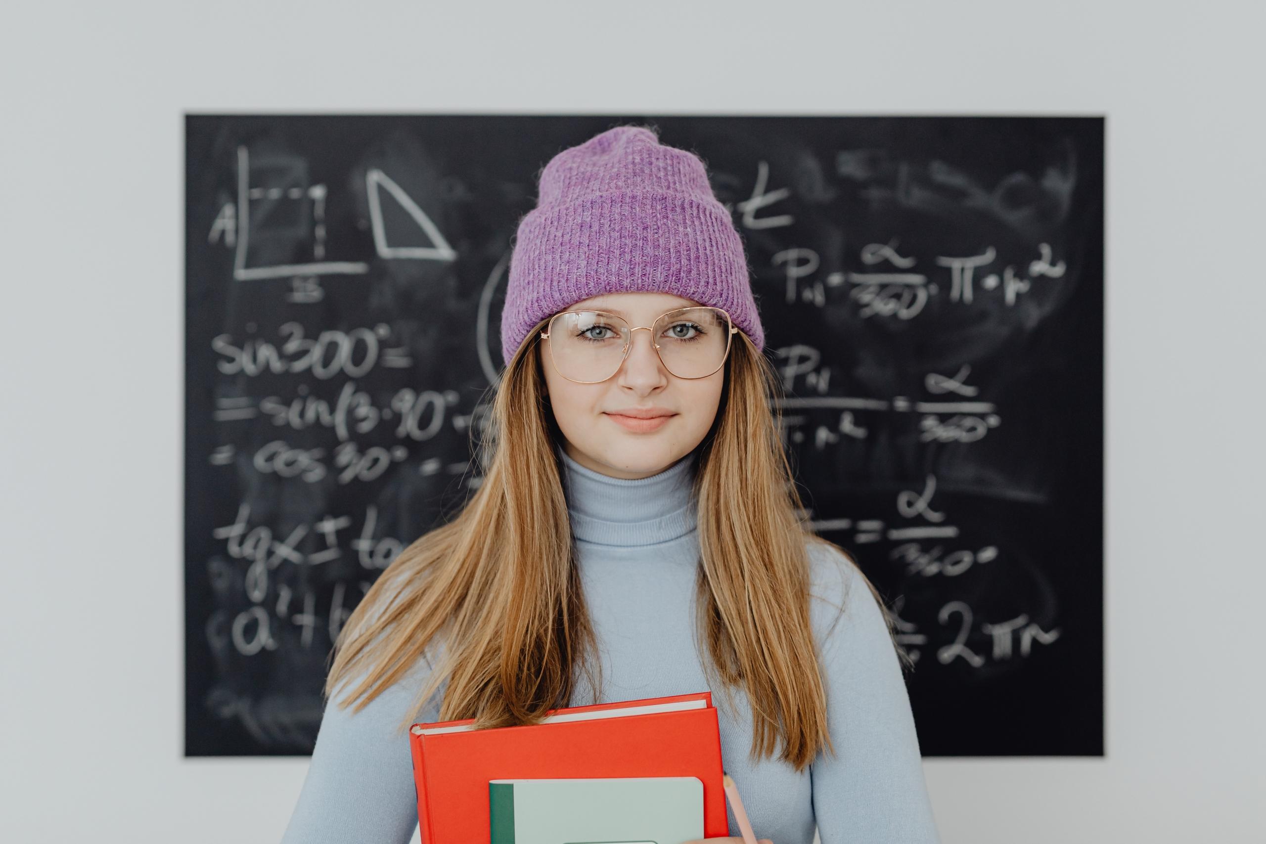 student standing in front of blackboard covered in maths equations