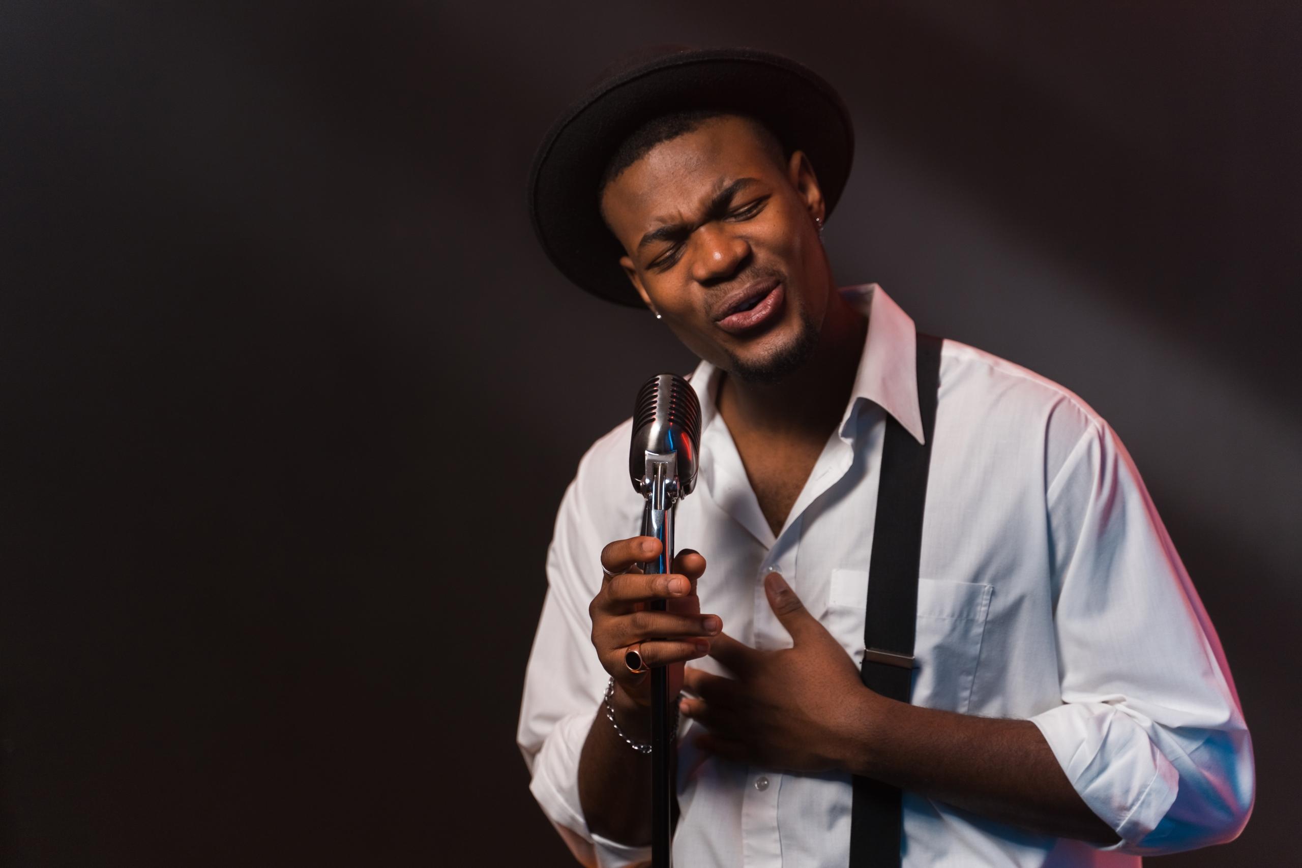 well-dressed man singing into mic on stage