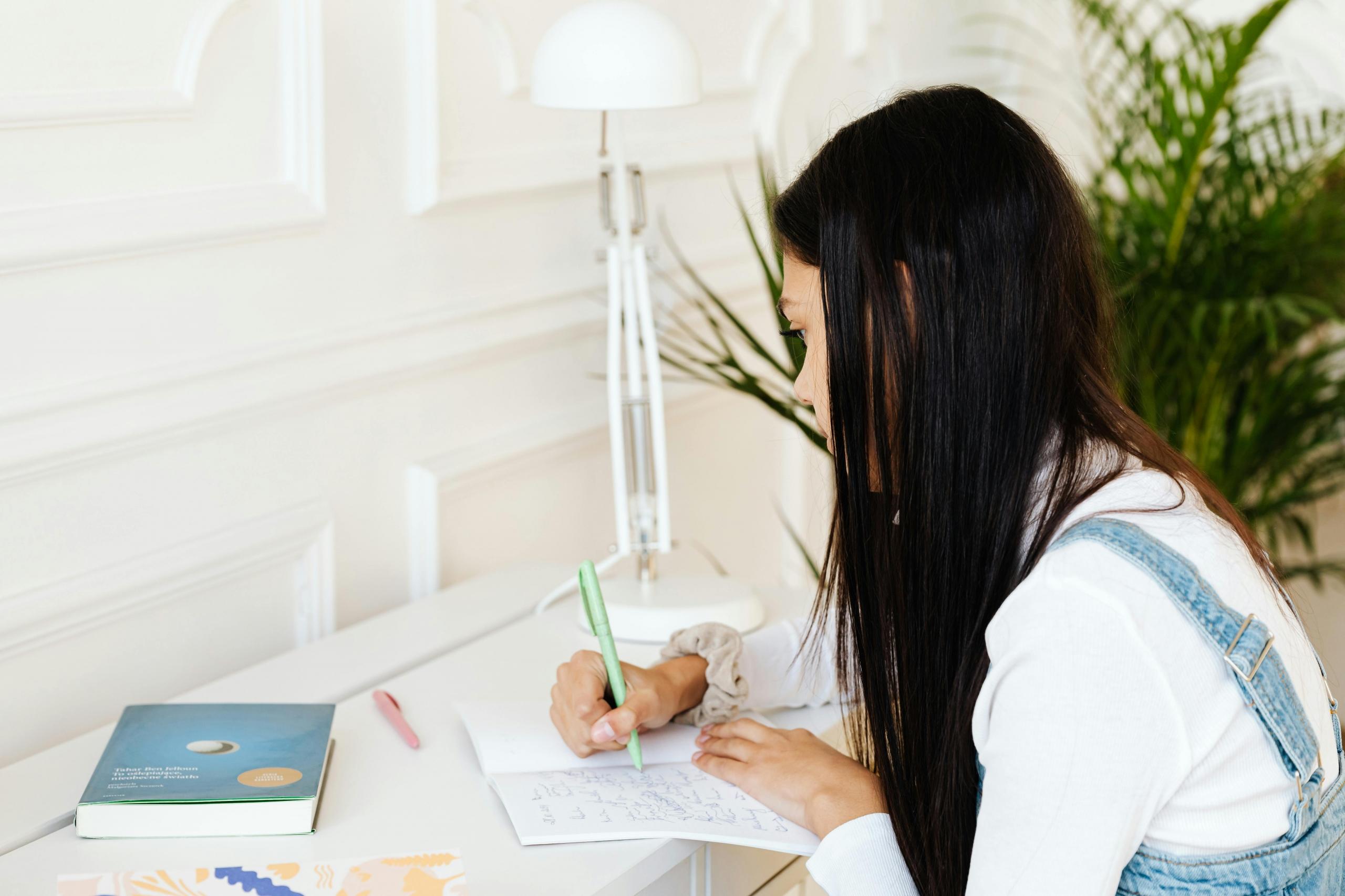girl sitting at desk studying using notebook an textbook