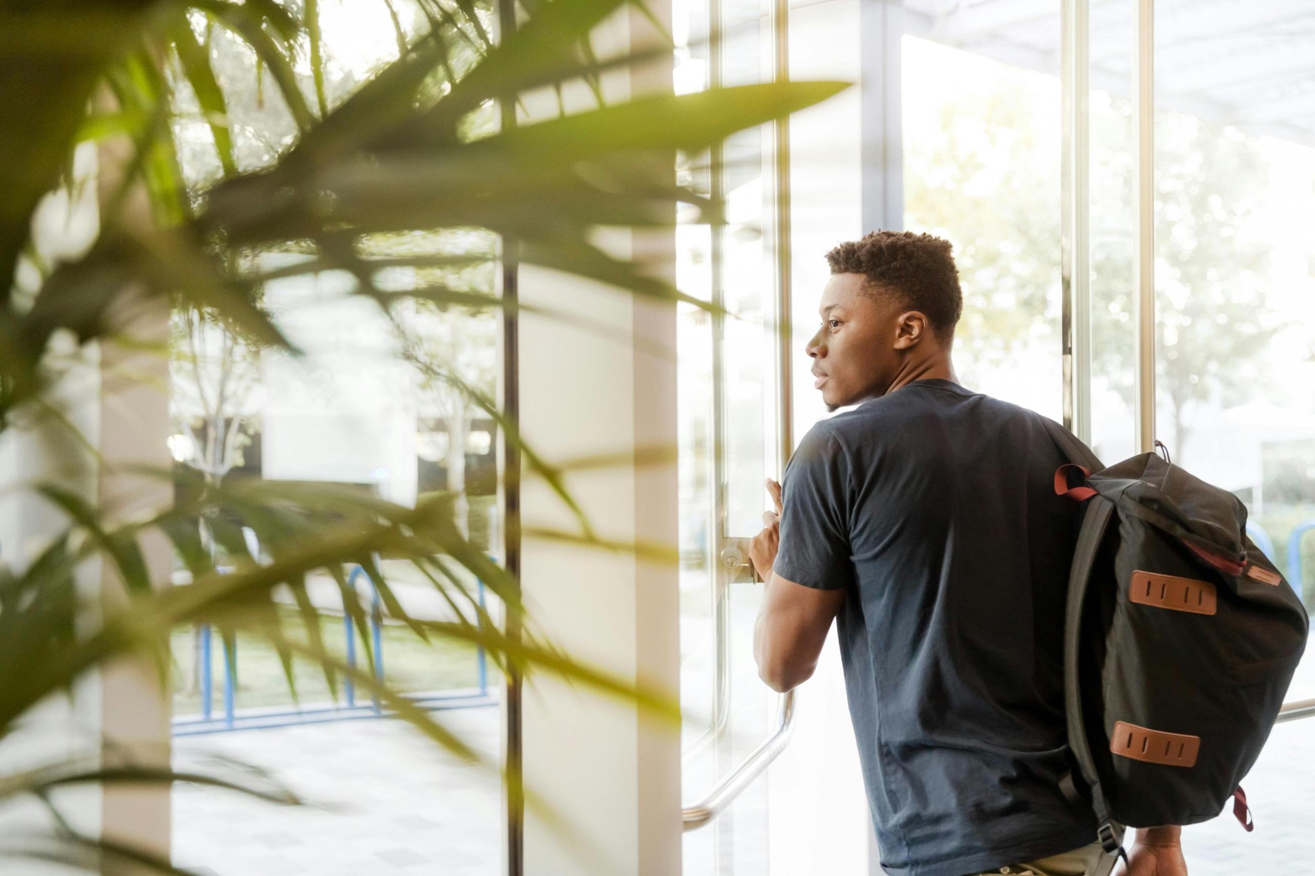 boy wearing backpack walking out of building