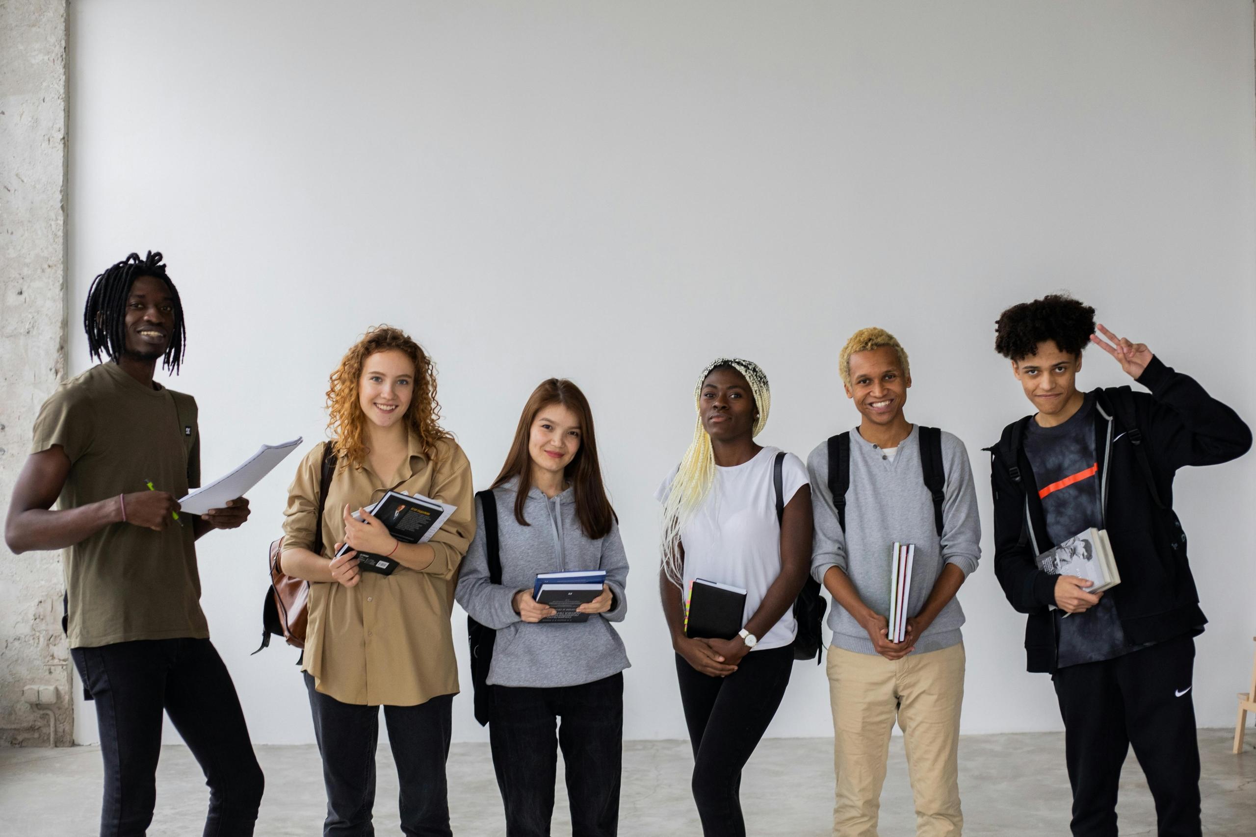 group of teens standing side-by-side holding school books