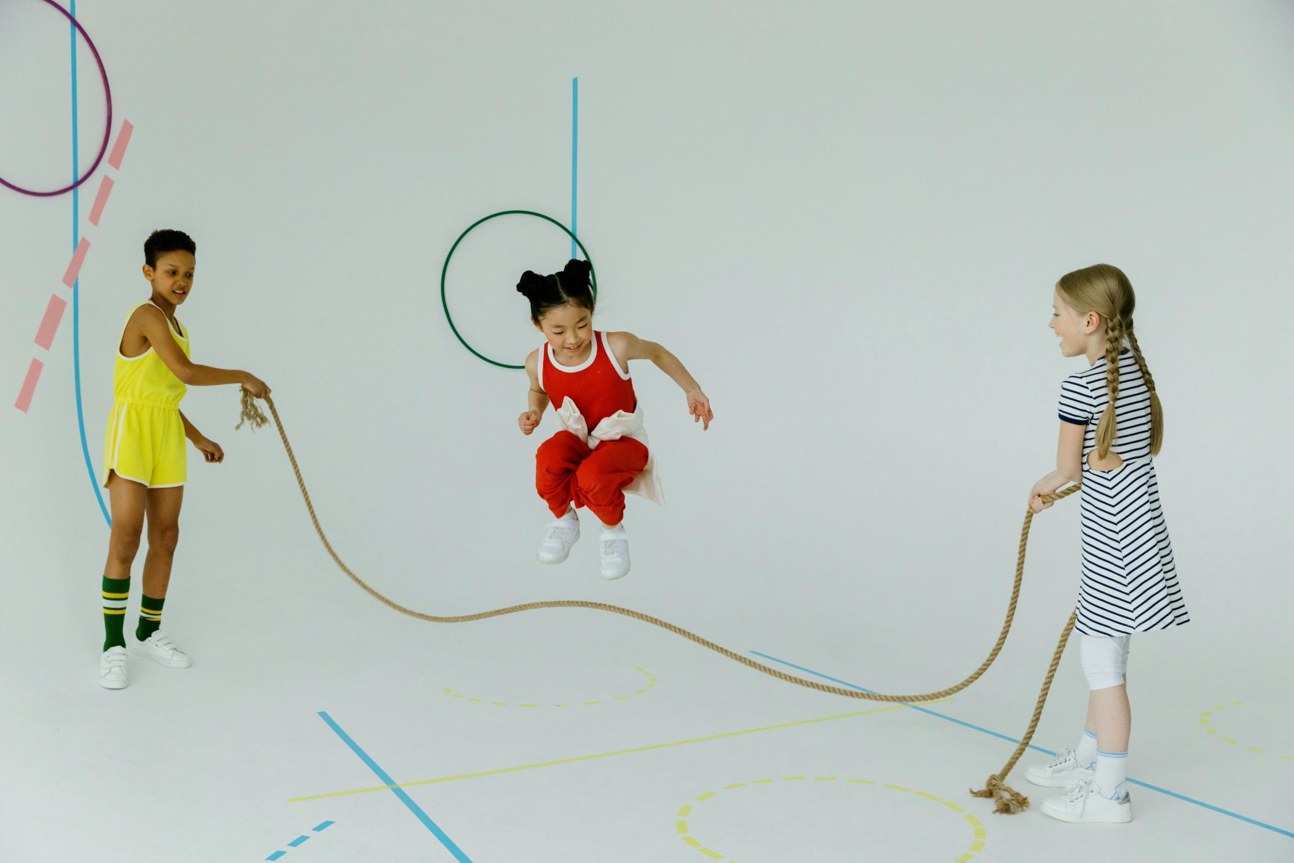 three girls playing with skipping rope in white room
