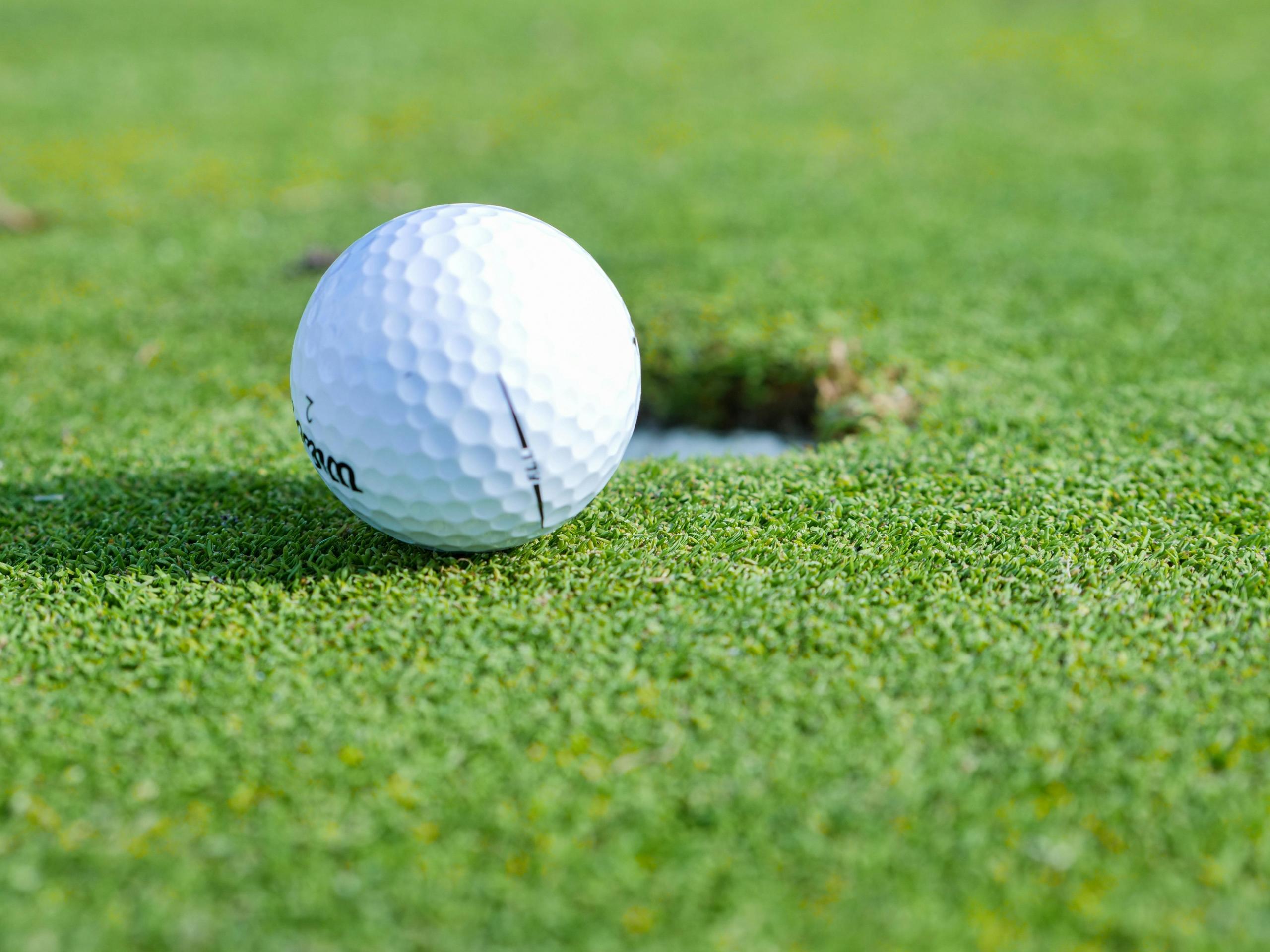 white golf ball beside golf cup on green grass