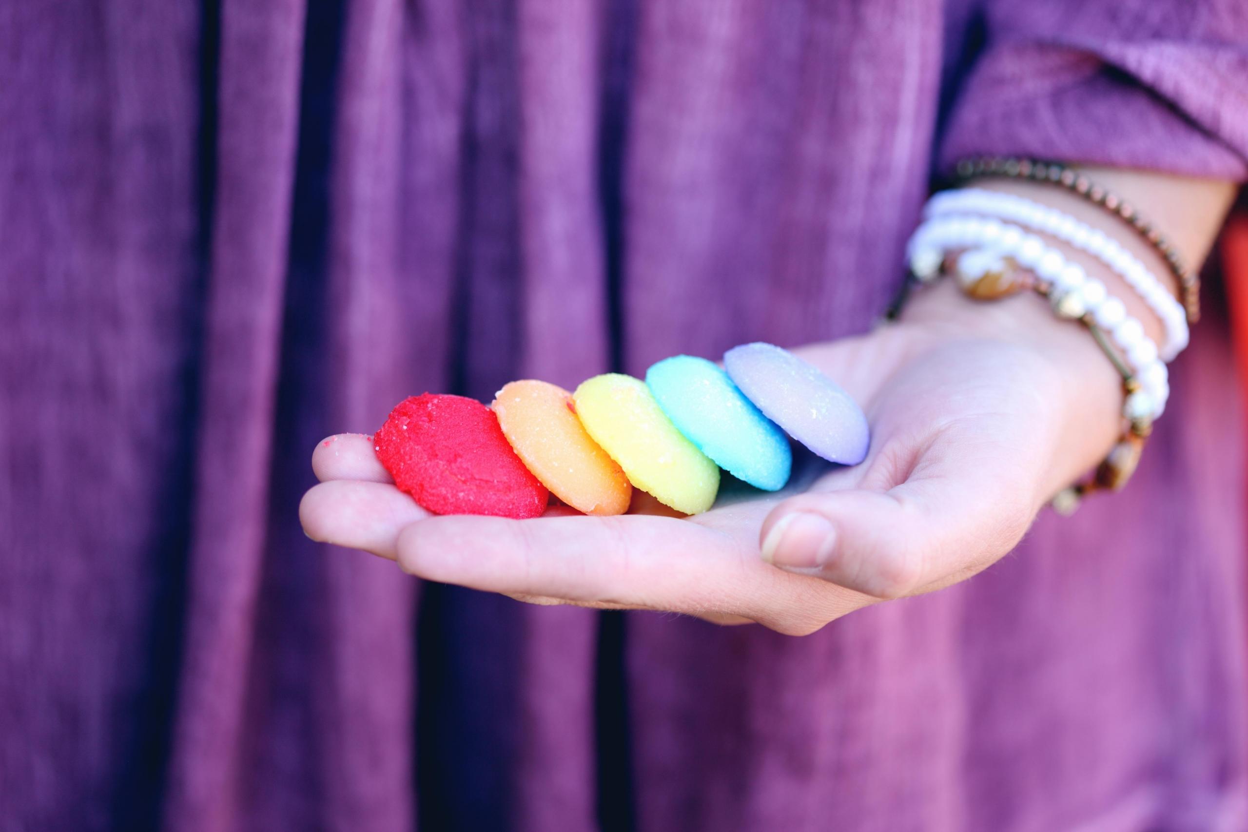 woman in purple dress holding a selection of brightly coloured biscuits in her hand