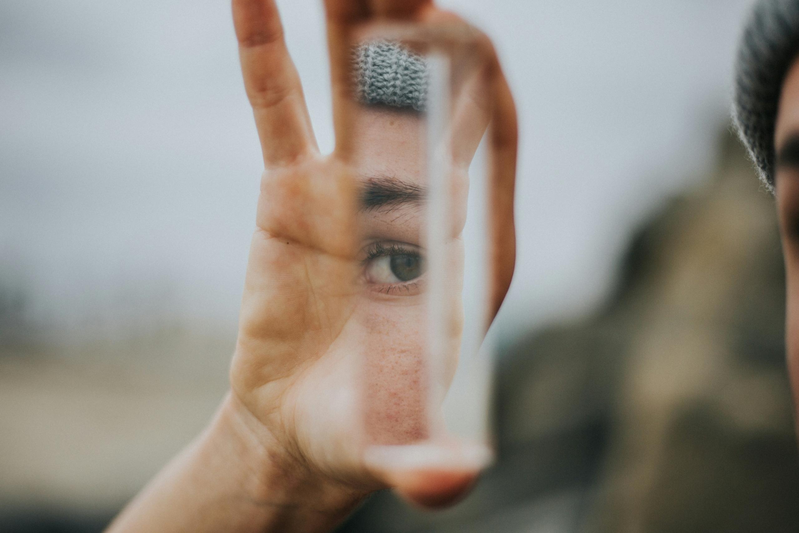 reflection of eye in small rectangular mirror held in someone's hand