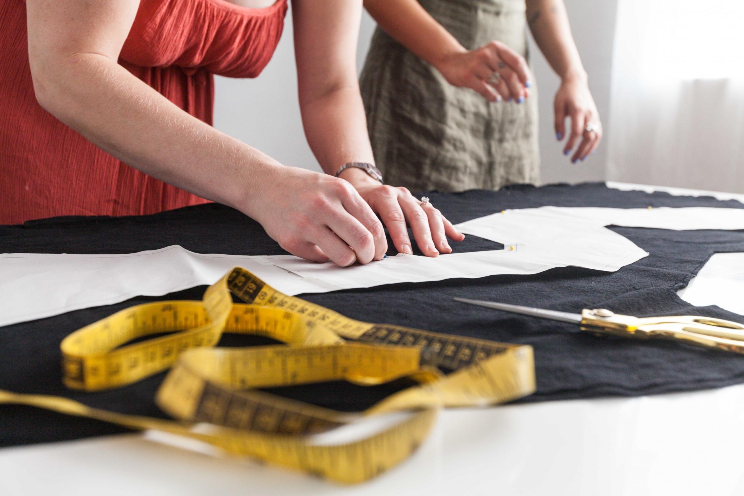 sewing teacher observing as student traces pattern onto black fabric