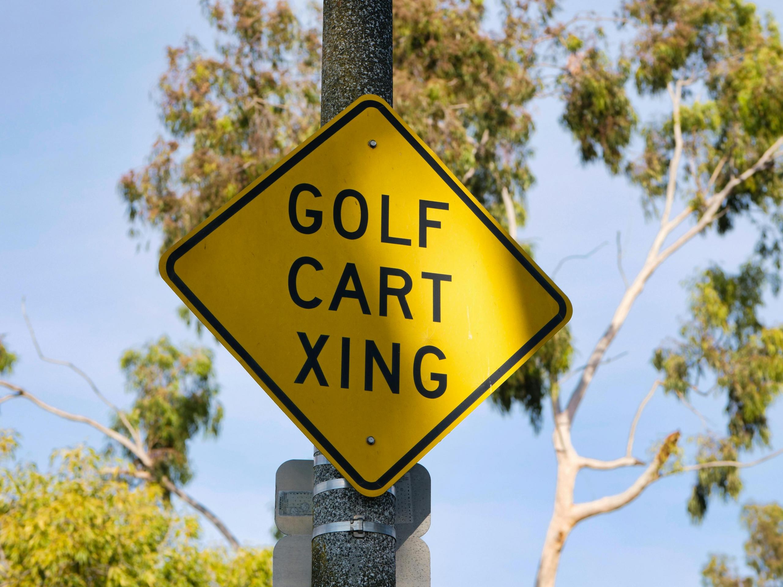 yellow street sign warning of golf carts crossing