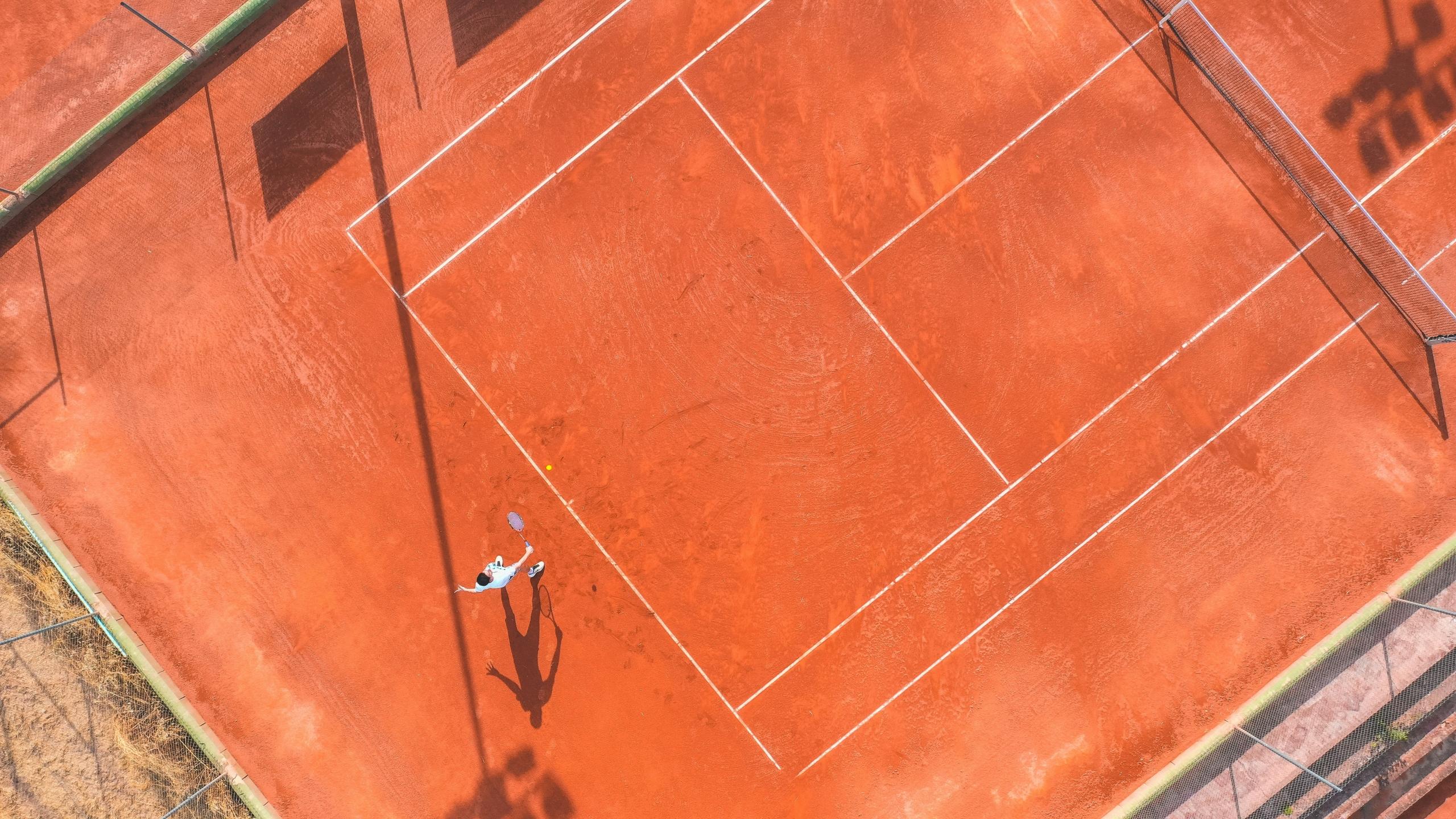 aerial view of tennis player on clay court about to return a serve