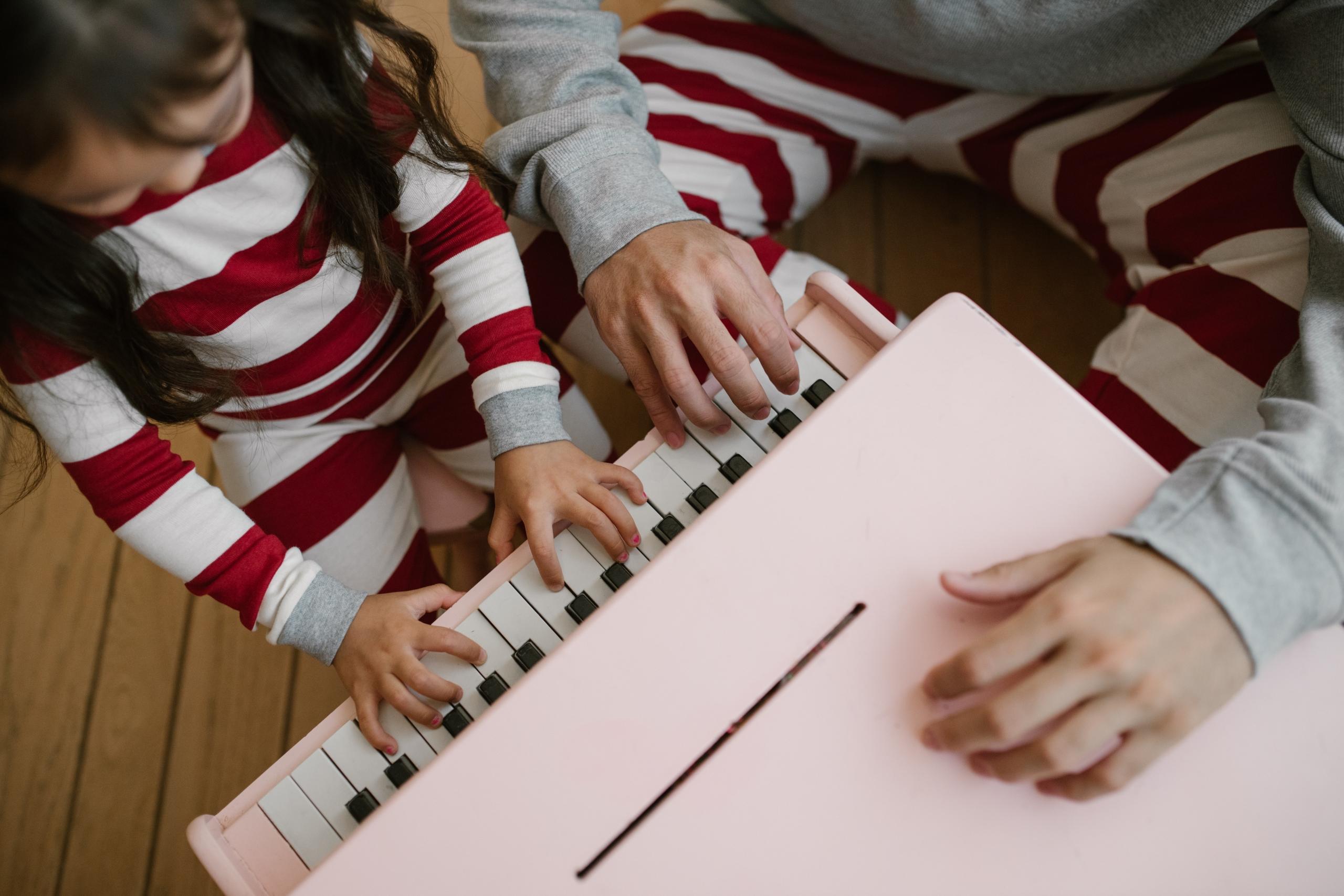 young girl in pyjamas playing a miniature pink piano