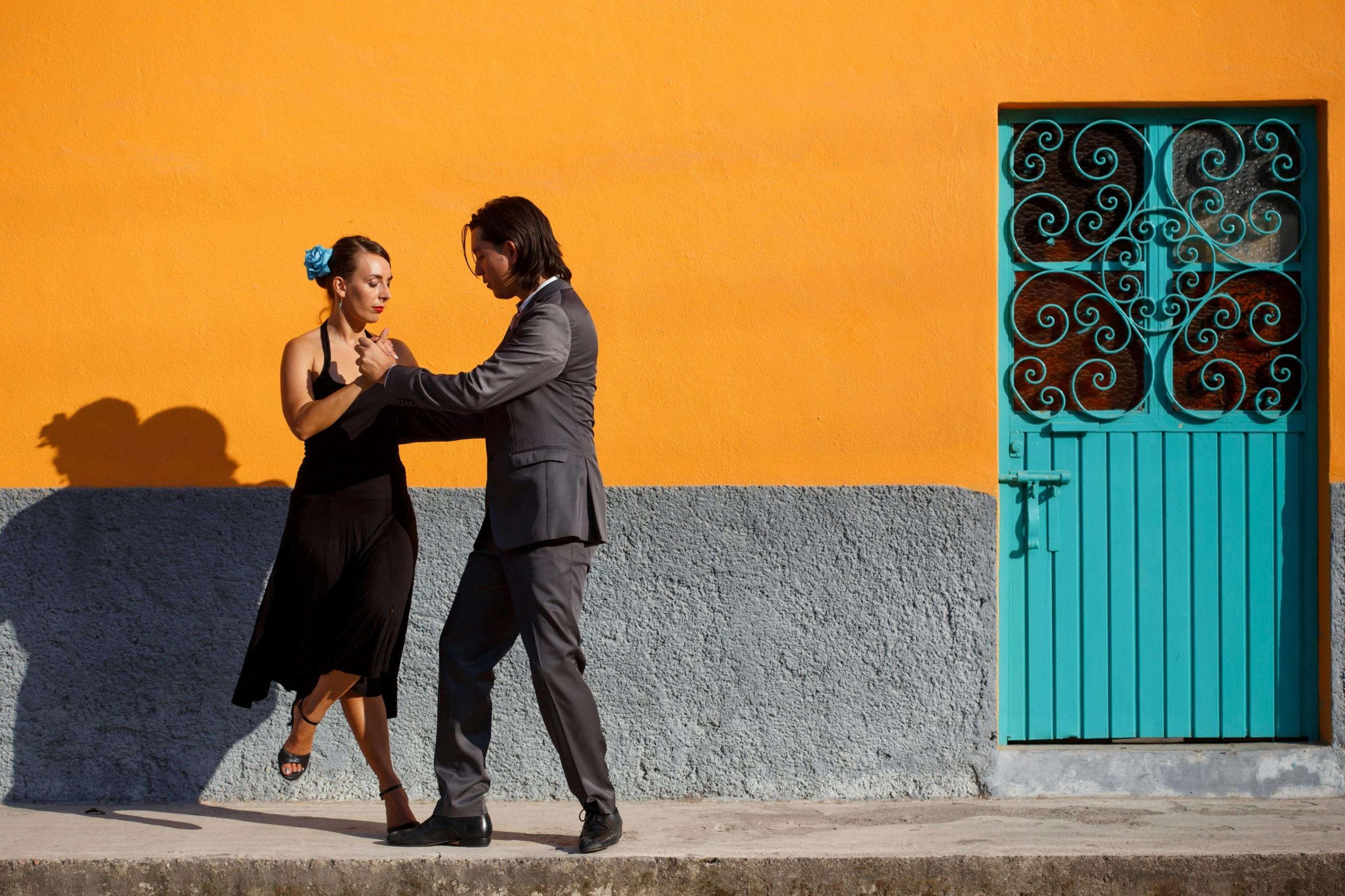man and woman dancing the tango in front of brightly coloured wall
