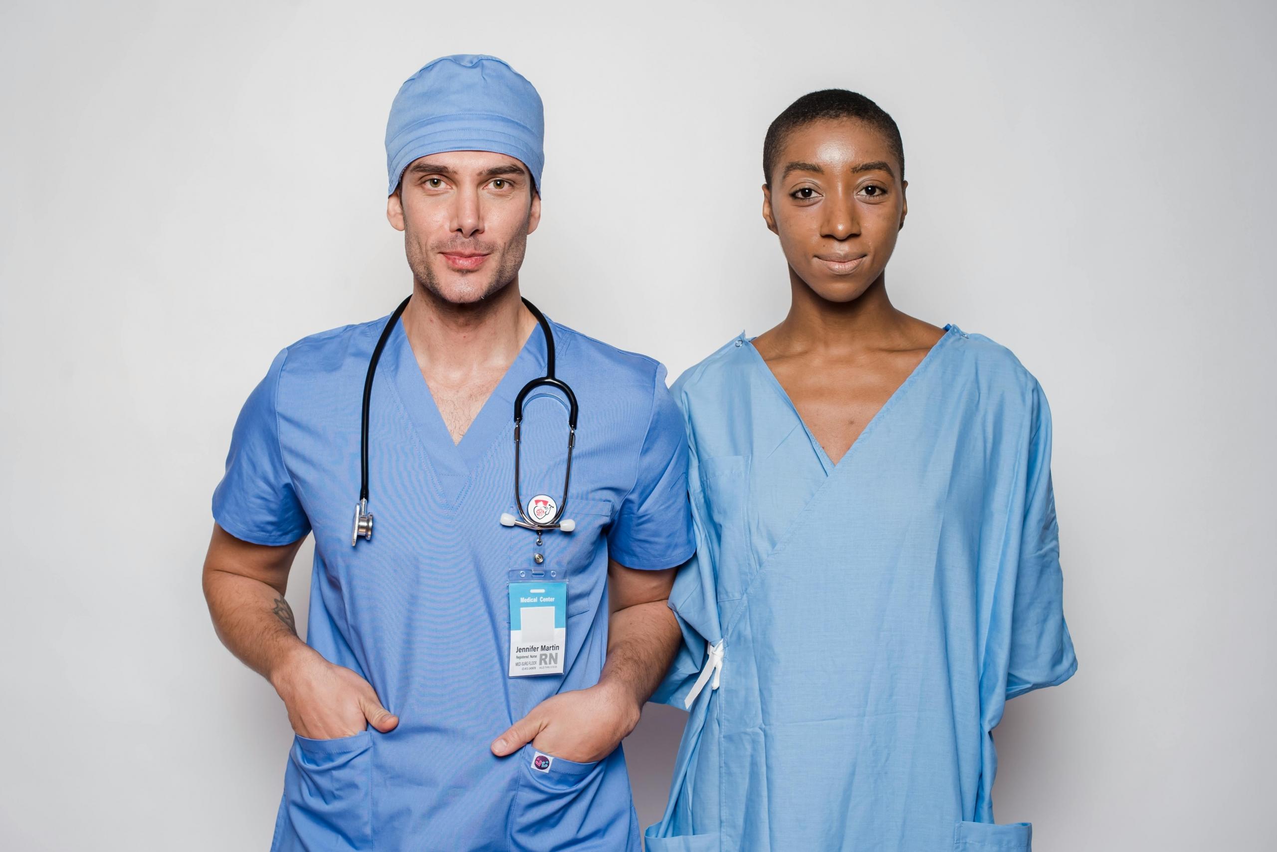 nurse standing next to doctor with stethoscope around his neck, both in blue scrubs