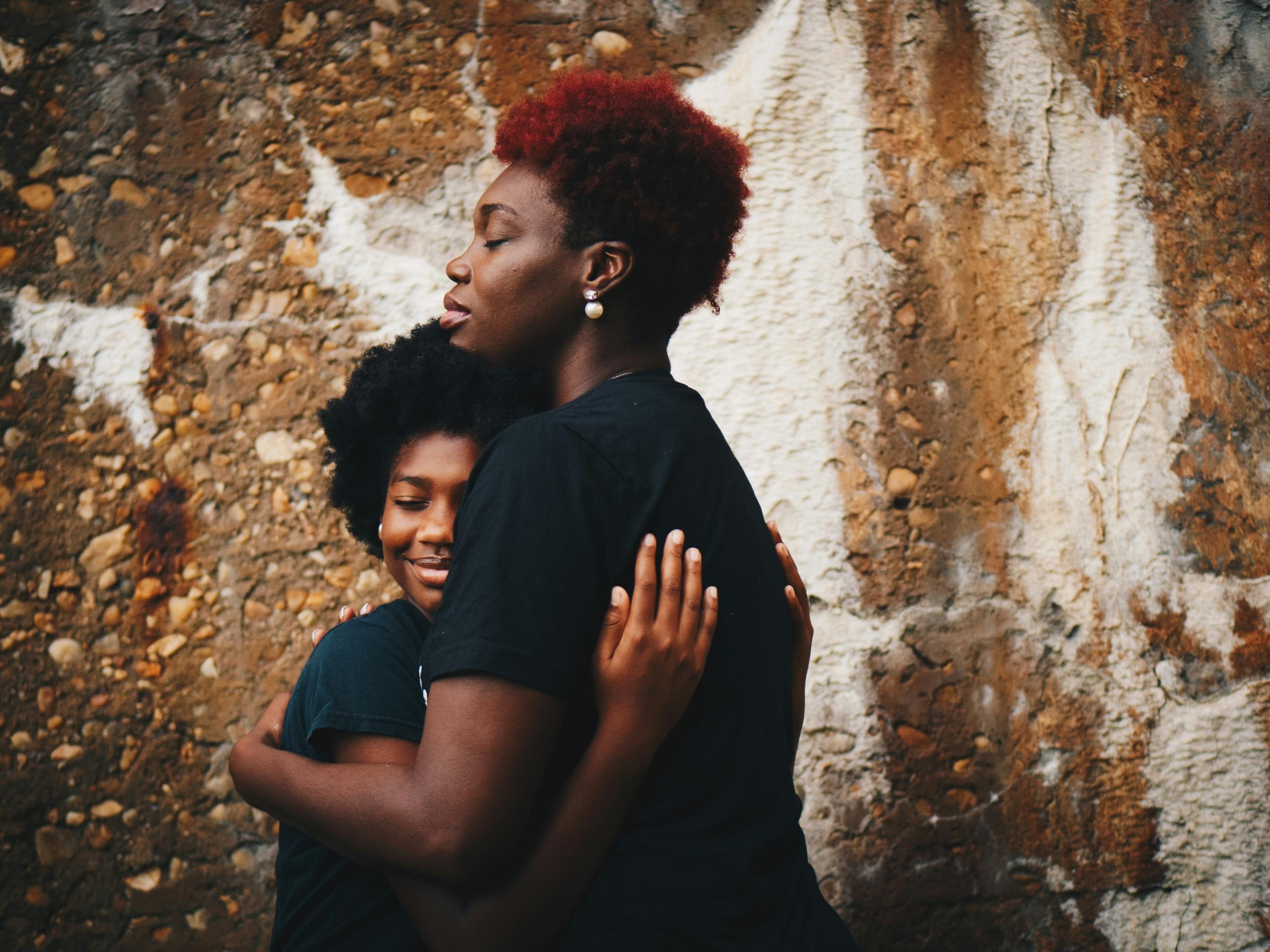 mom and son hugging in front of stone wall