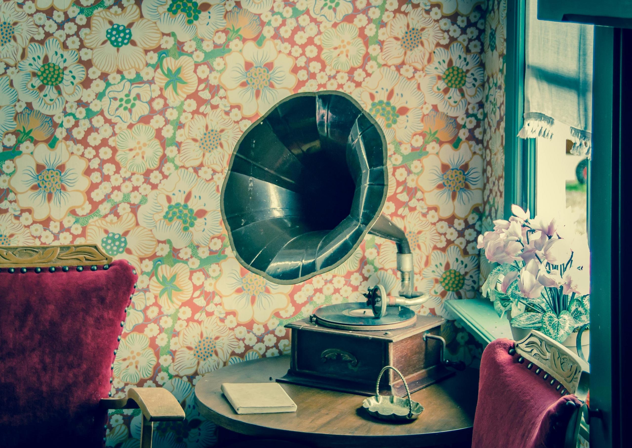 vintage gramophone on small table next to wallpapered wall