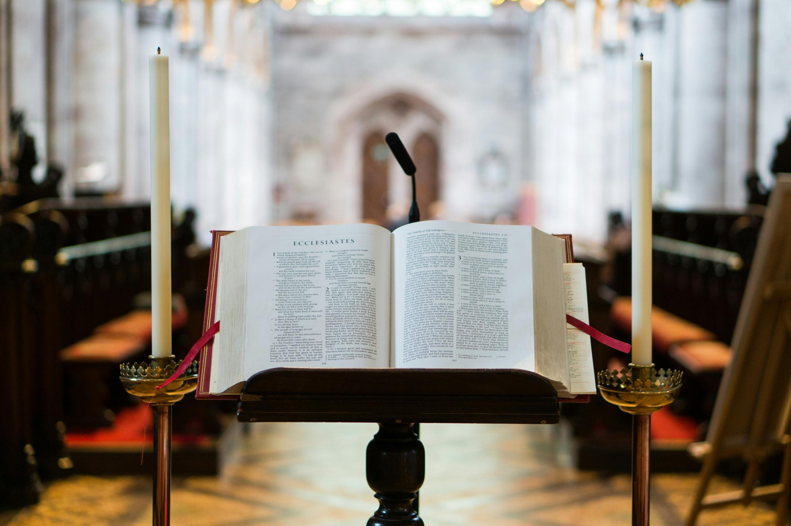 selective focus photography opened bible on lectern in front of church