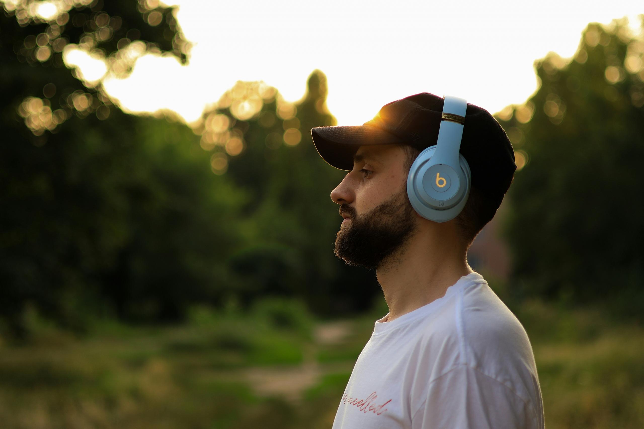 man wearing headphones standing in a field at dusk