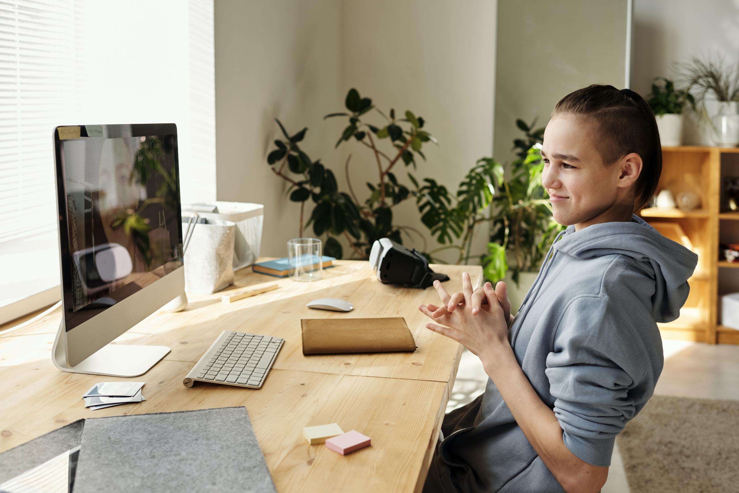 student sitting at desk using desktop computer to sign into online lesson