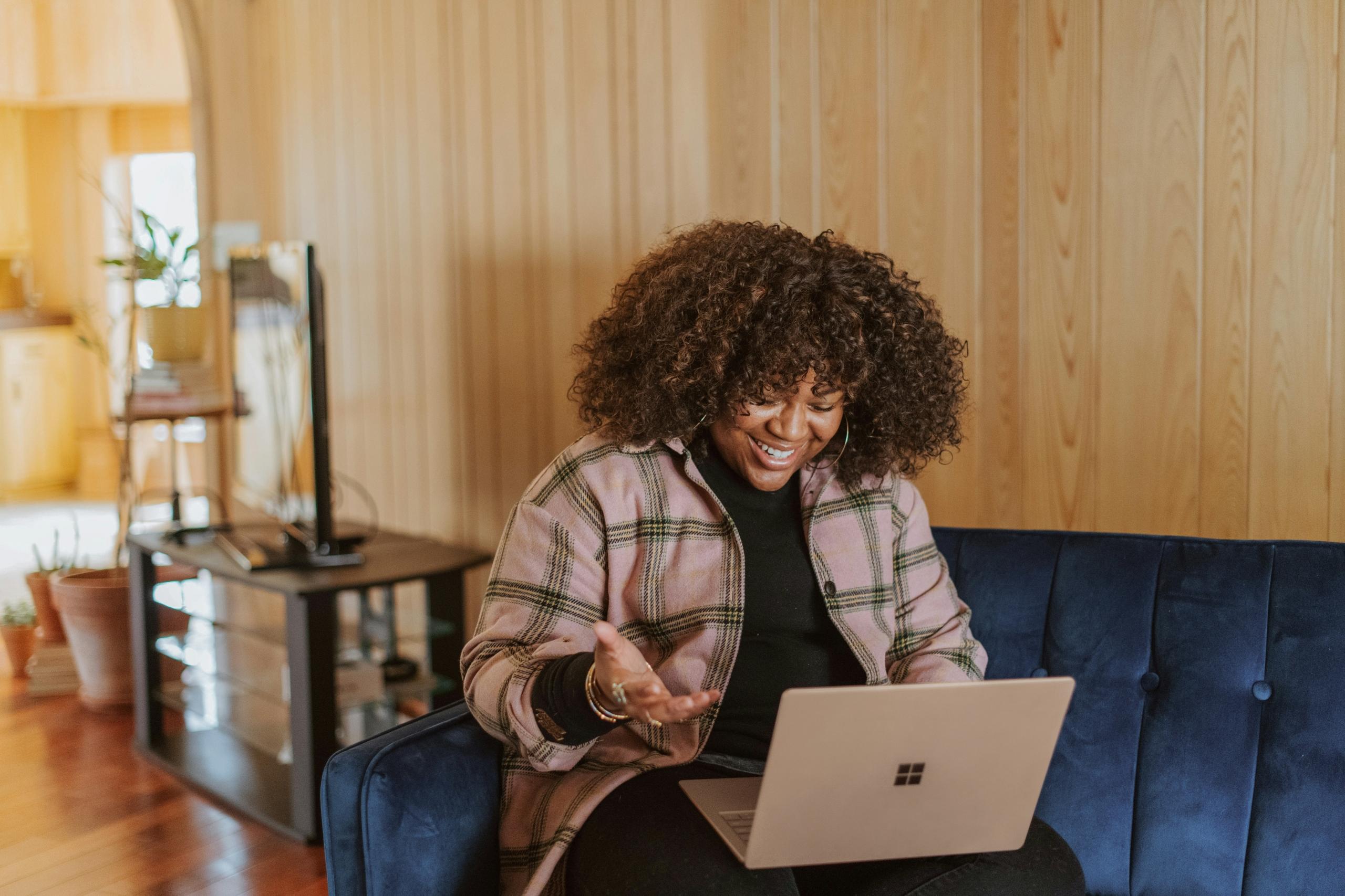 smiling woman sitting on couch using laptop