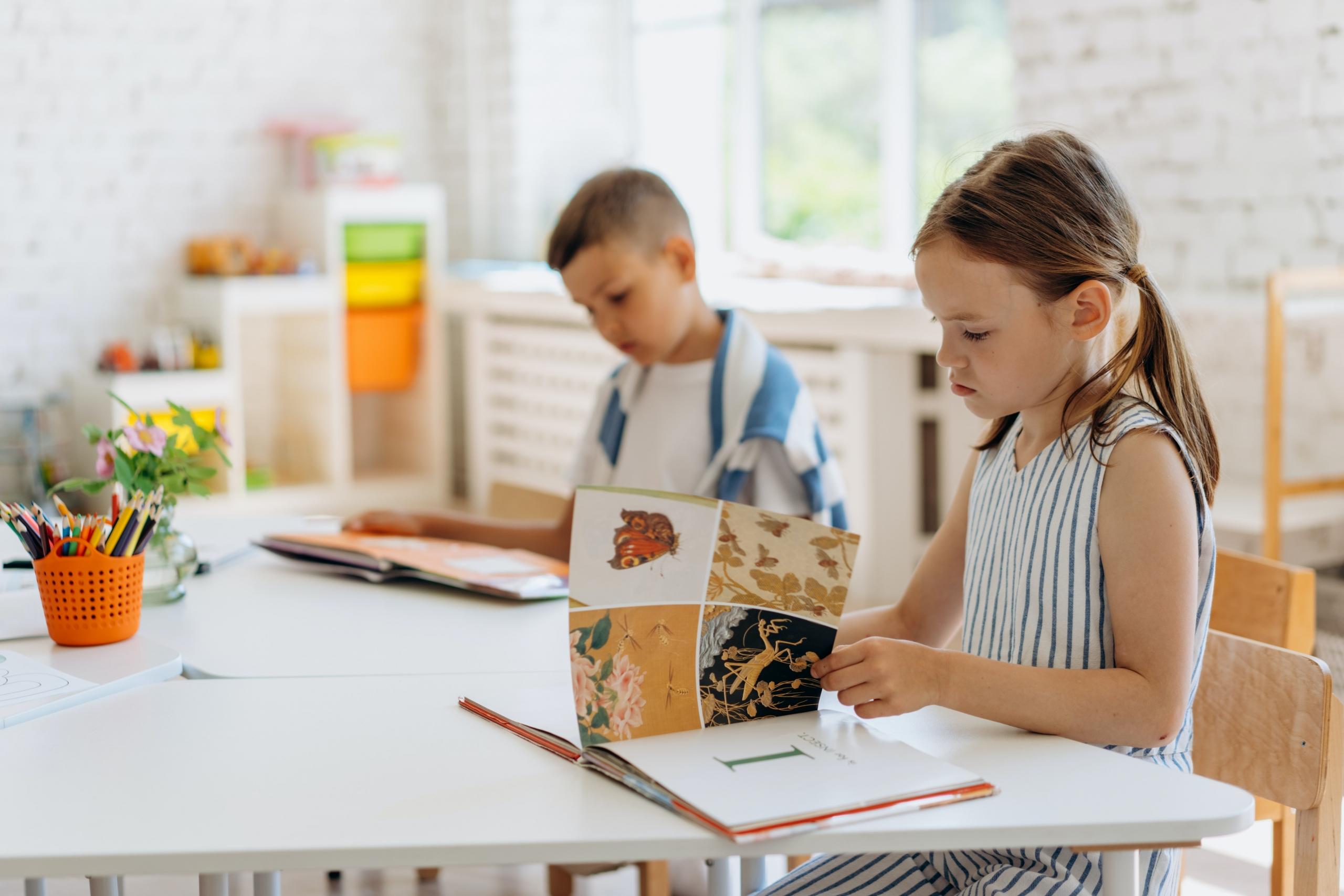 boy and girl sitting at classroom table reading picture books