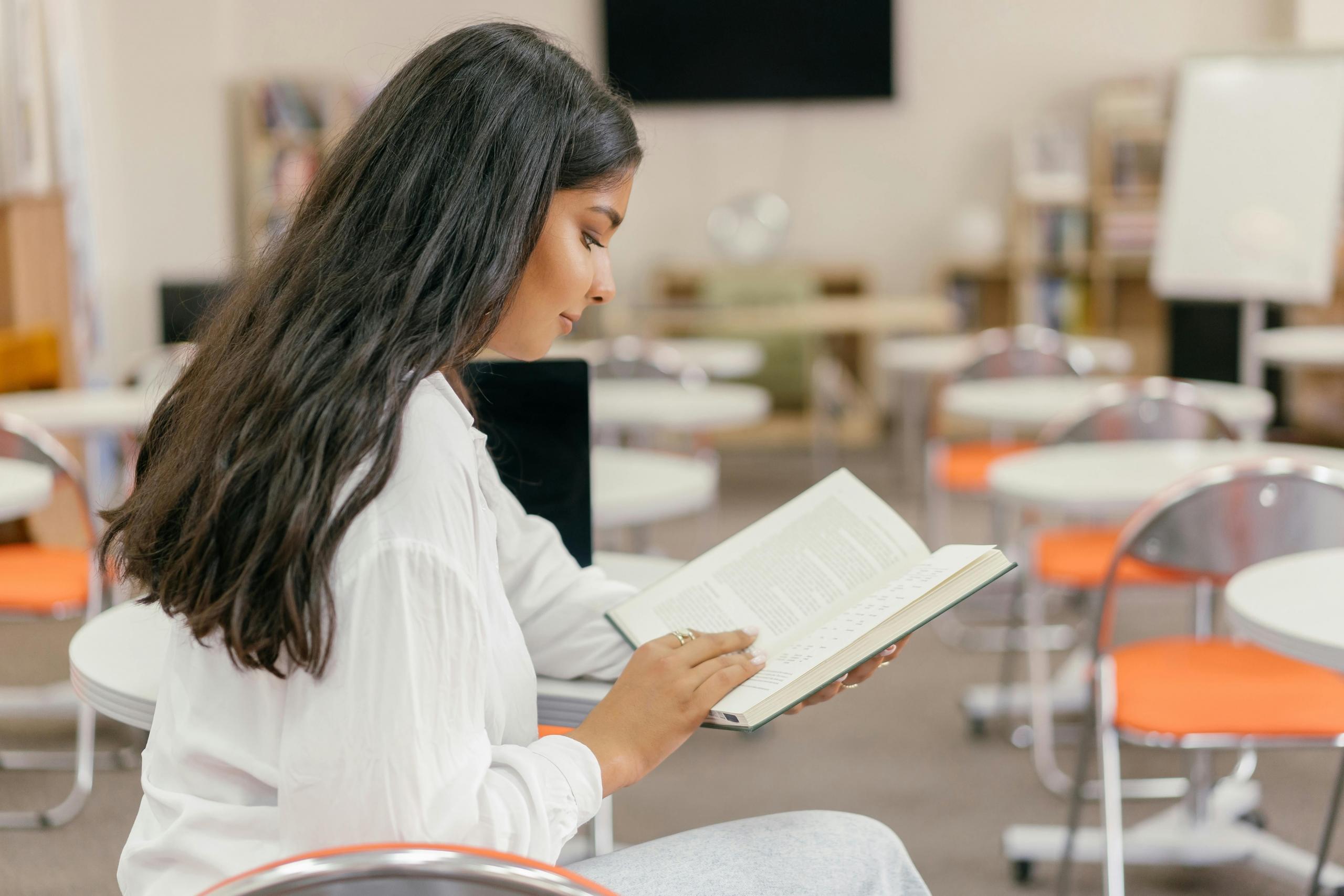 teen sitting in classroom reading a textbook
