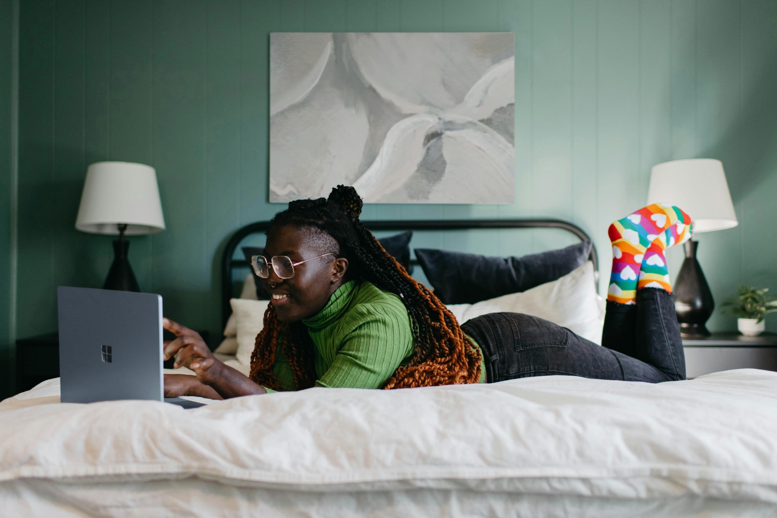 girl lying on bed typing on laptop keyboard