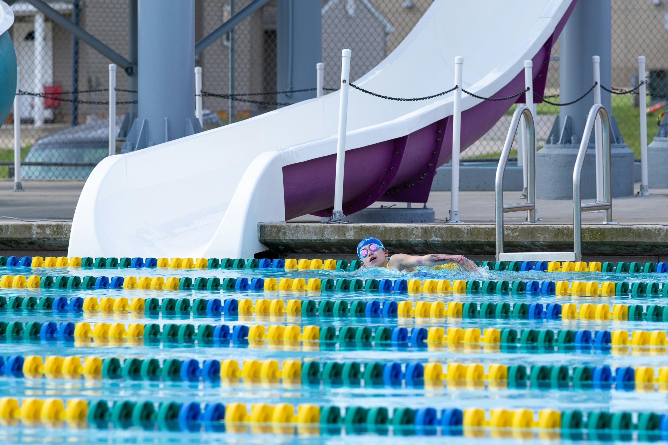 swimmer wearing goggles and swimming cape swimming laps in pool lanes