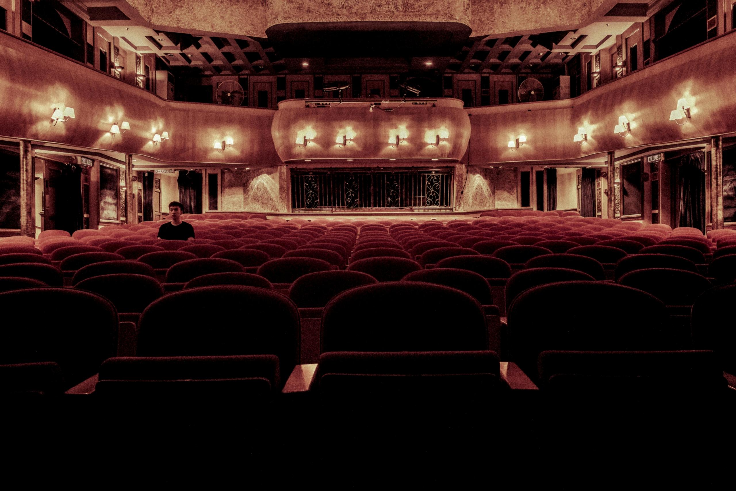 man sitting alone in dimly lit theatre