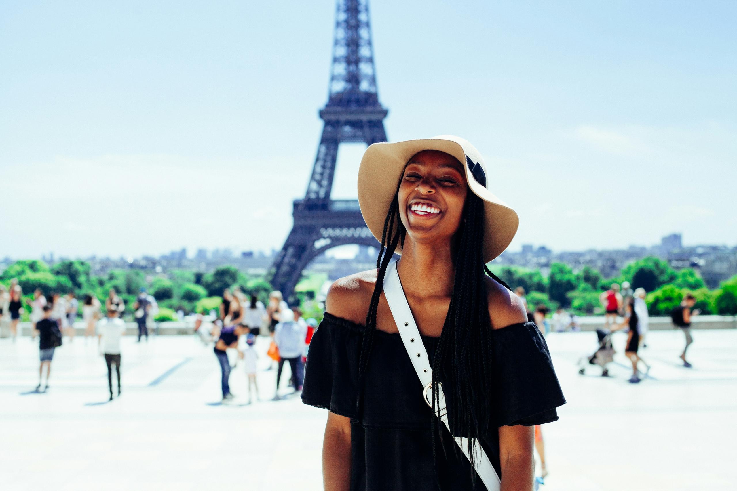 smiling woman standing on place du trocadero in front of the eiffel tower in paris