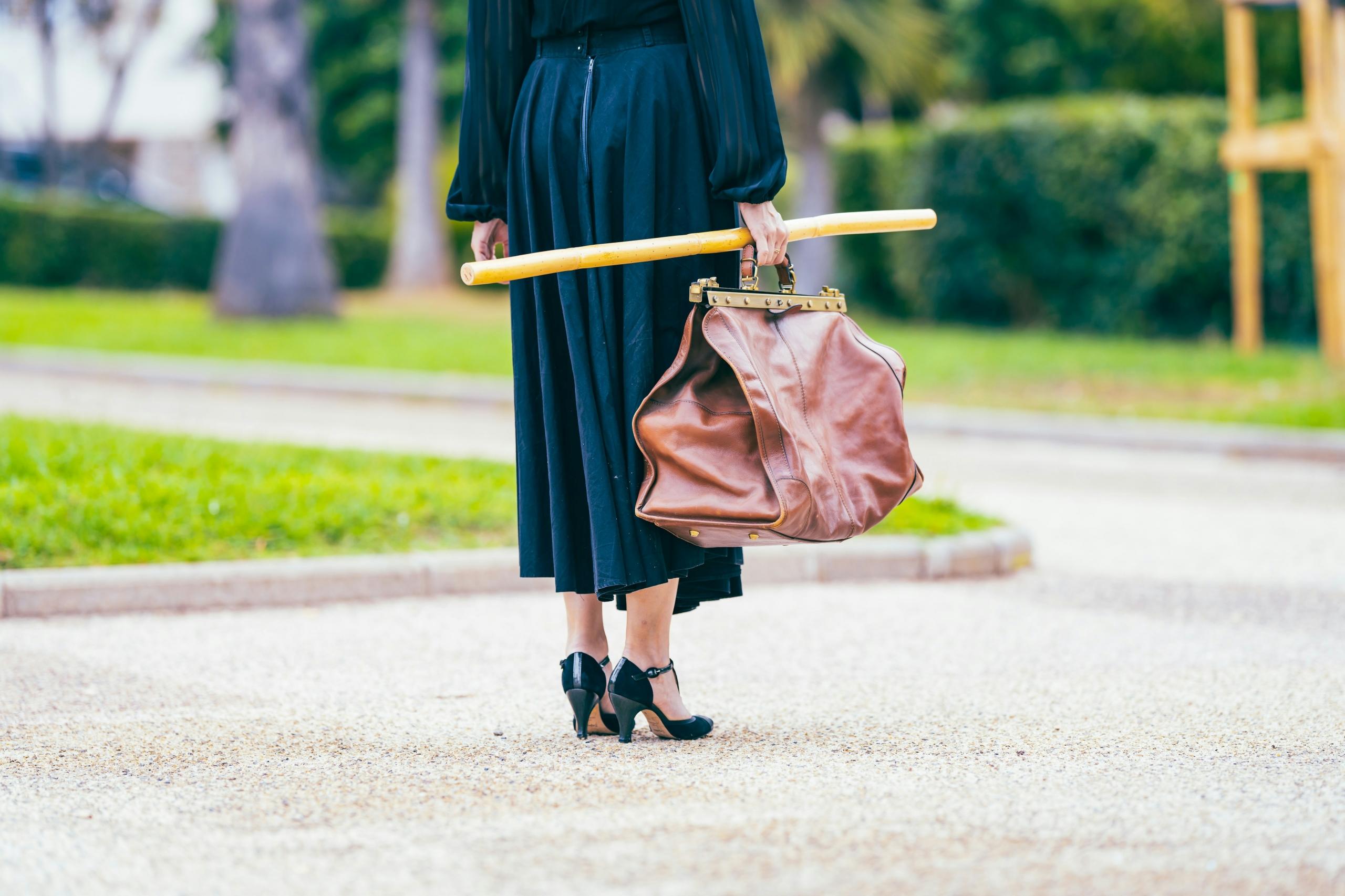 woman wearing babydoll shoes and carrying large leather bag and umbrella