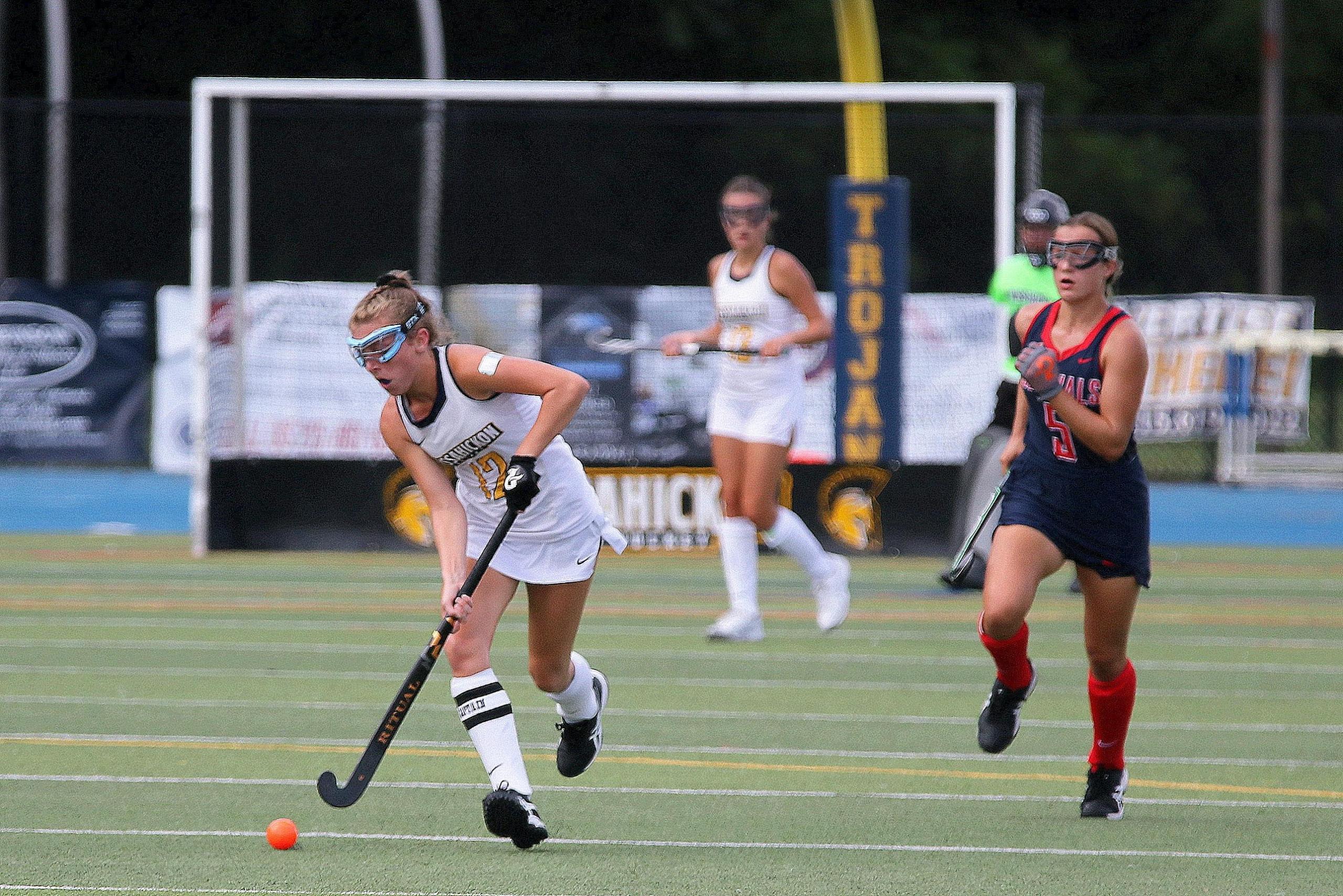 players running on hockey field wearing protective goggles