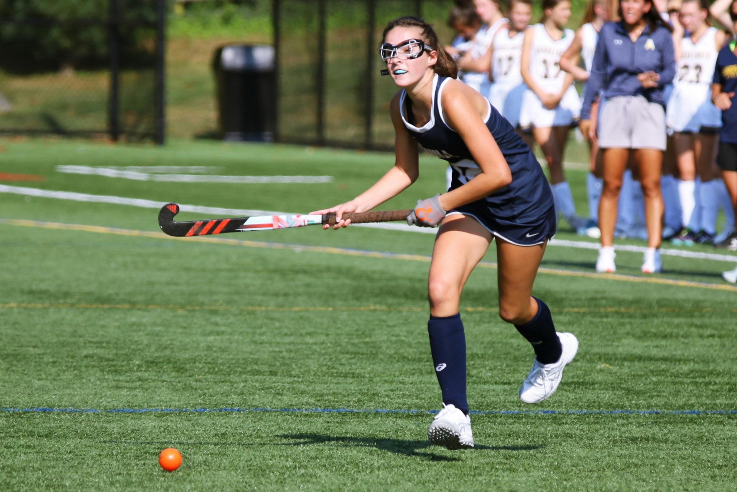 girl on hockey field wearing protective goggles and a mouthguard
