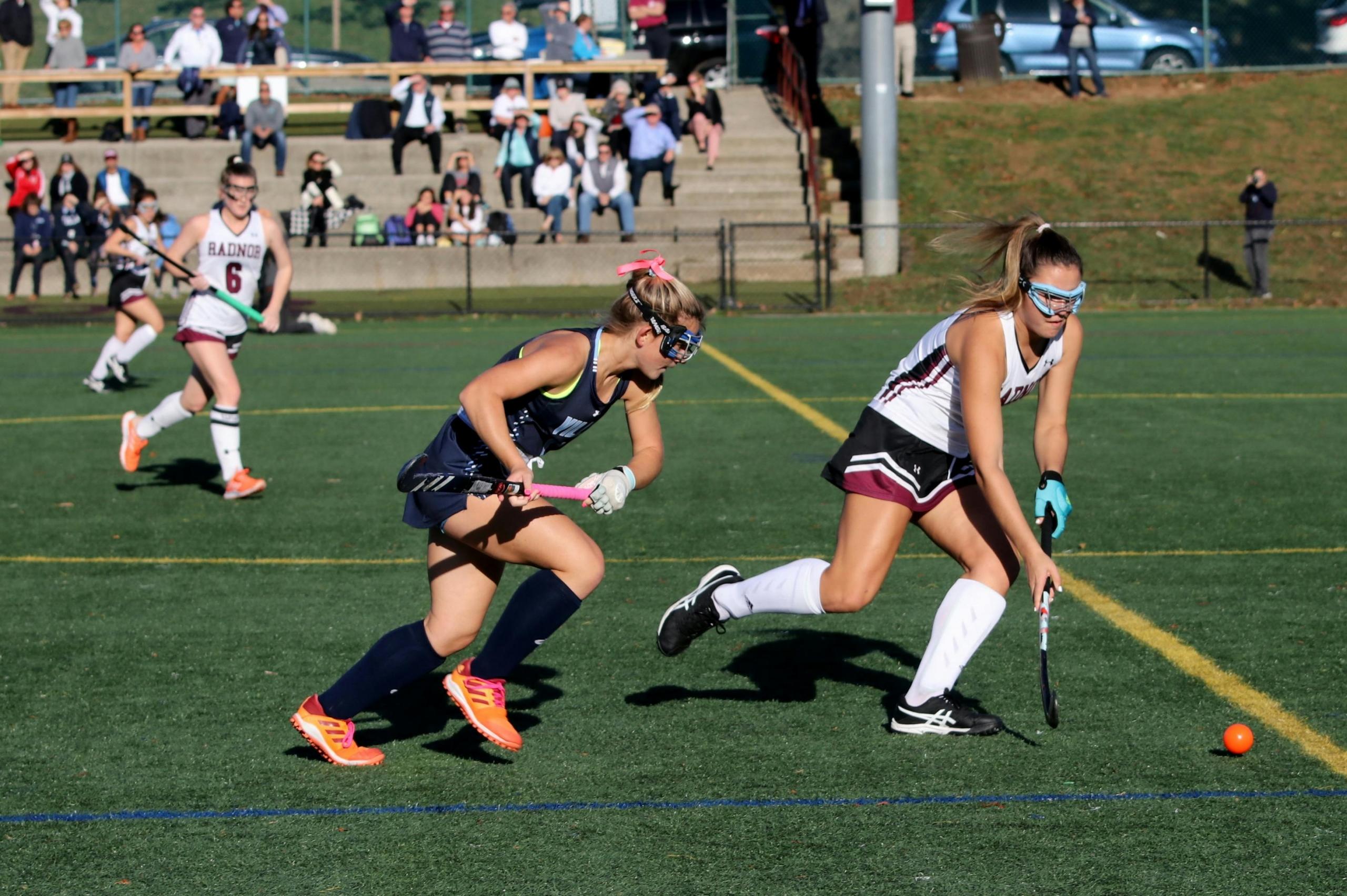 players running on hockey field wearing protective goggles and shin pads