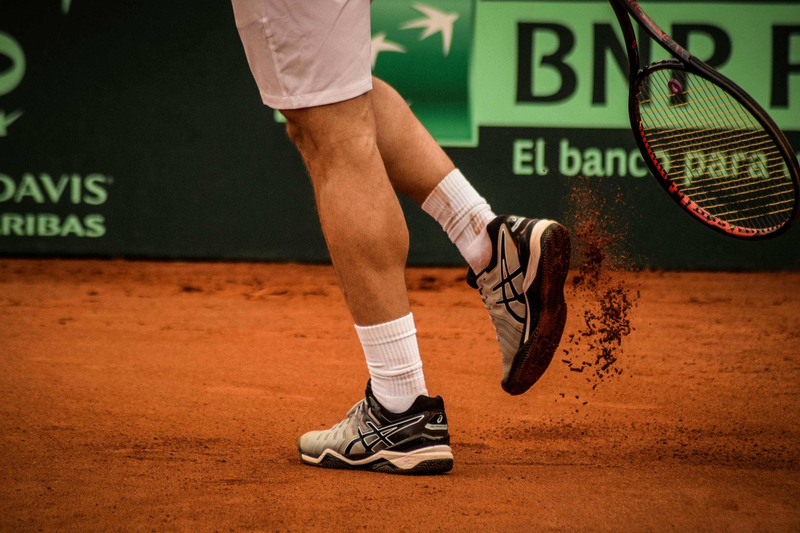 tennis player kicking up dirt during tennis match