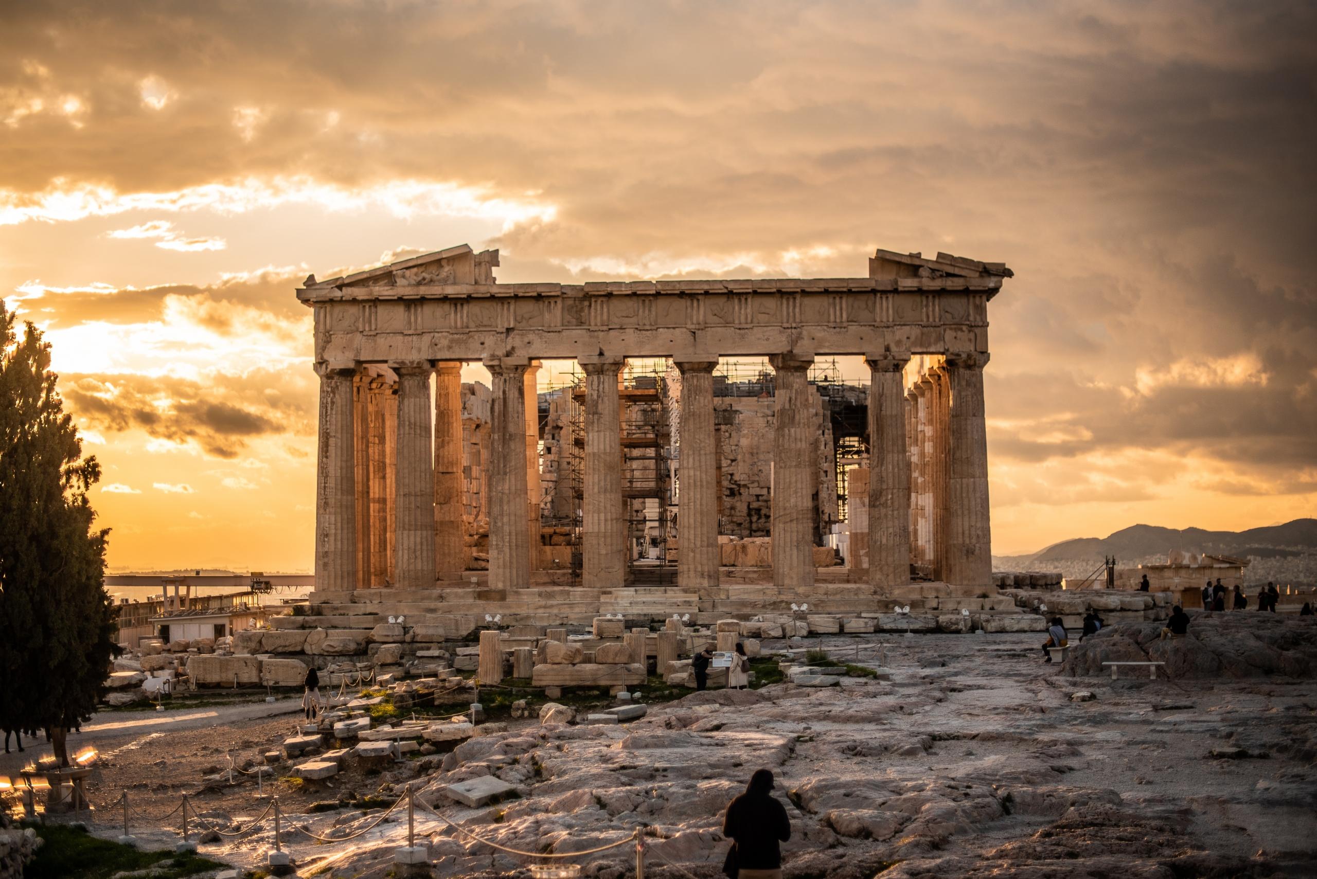 ancient ruins of Greek temple in Athens under cloudy sky at sunset