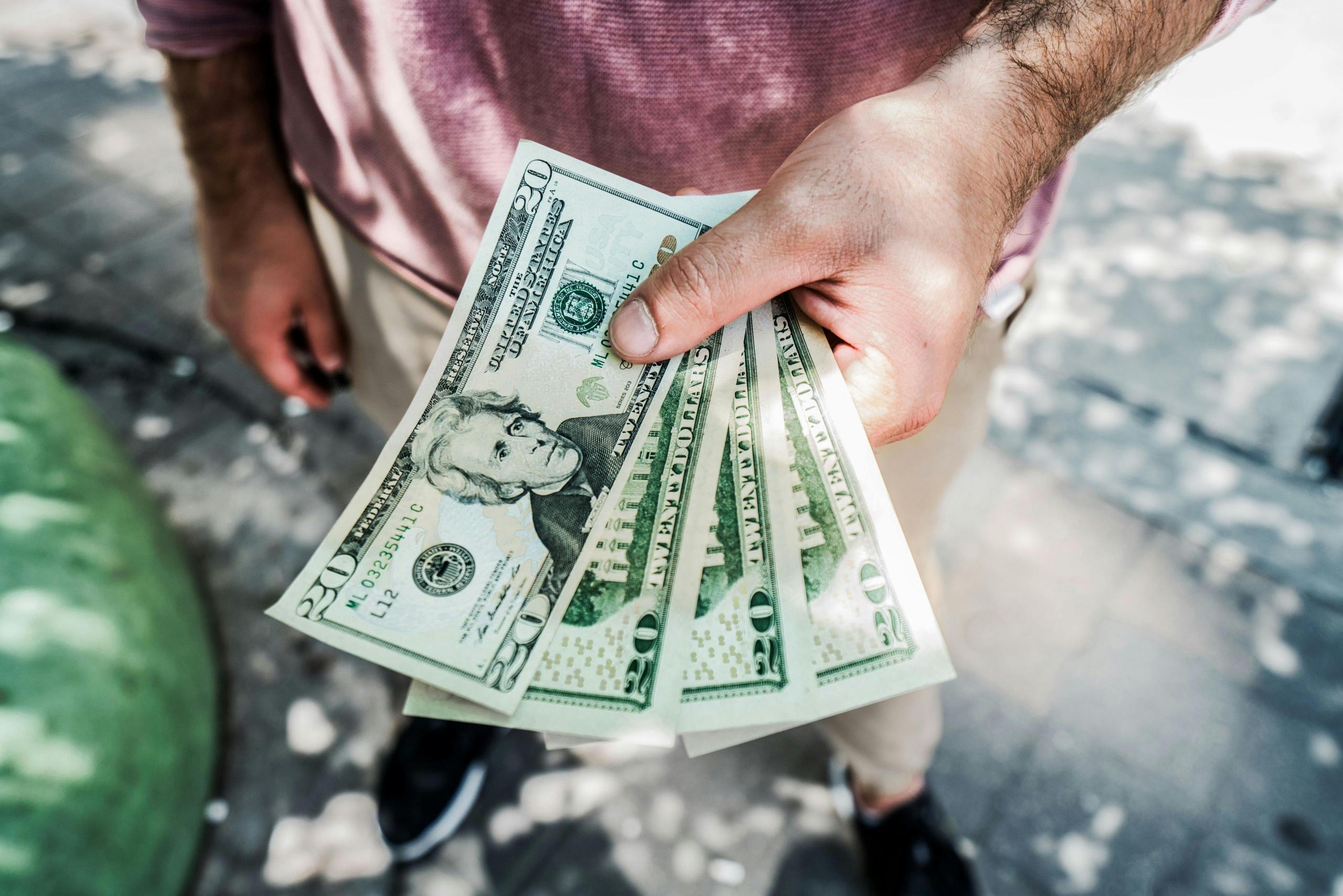 person holding fanned out dollar bank notes in hand