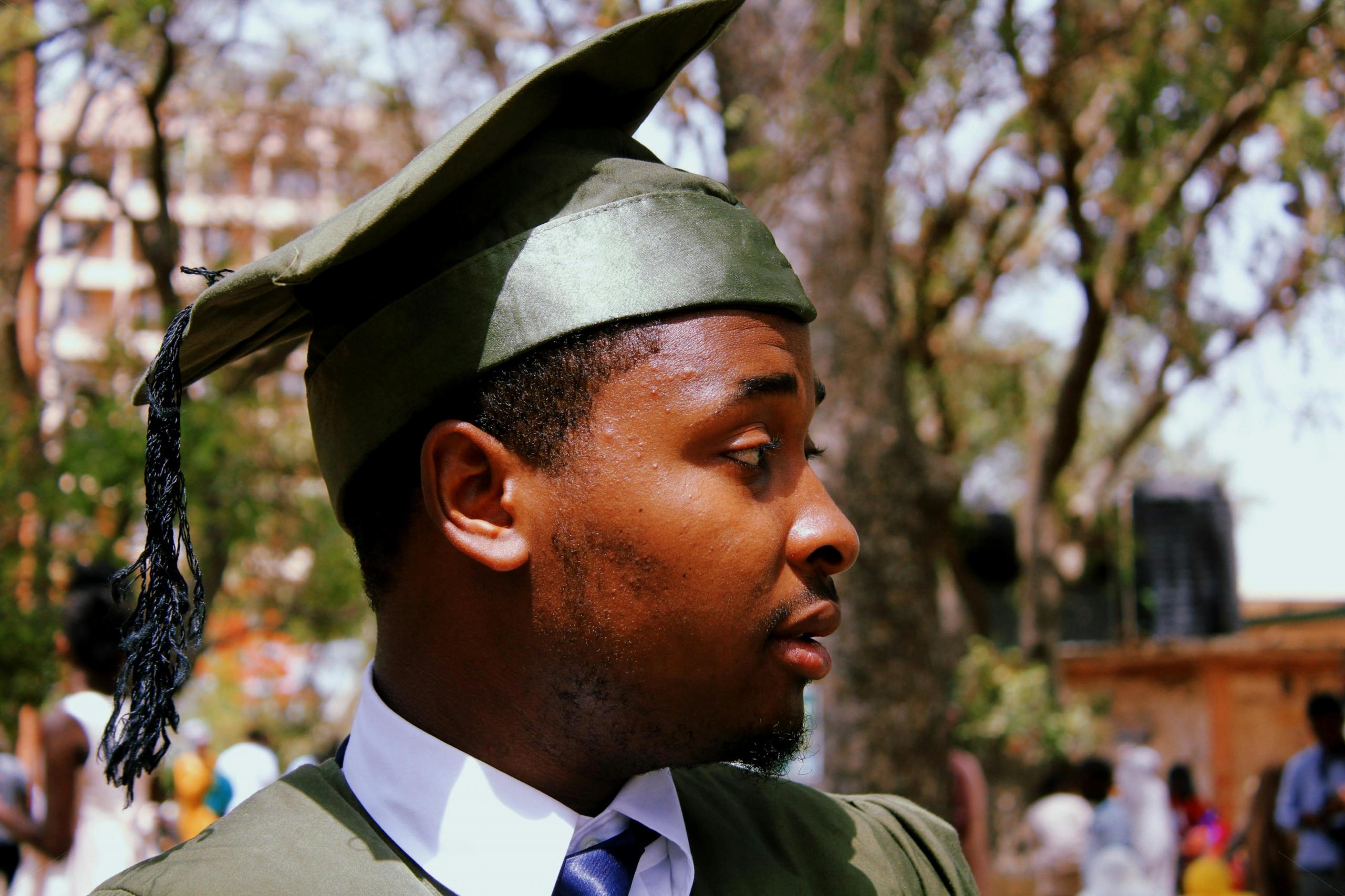 student graduating wearing green graduation gown and mortar board