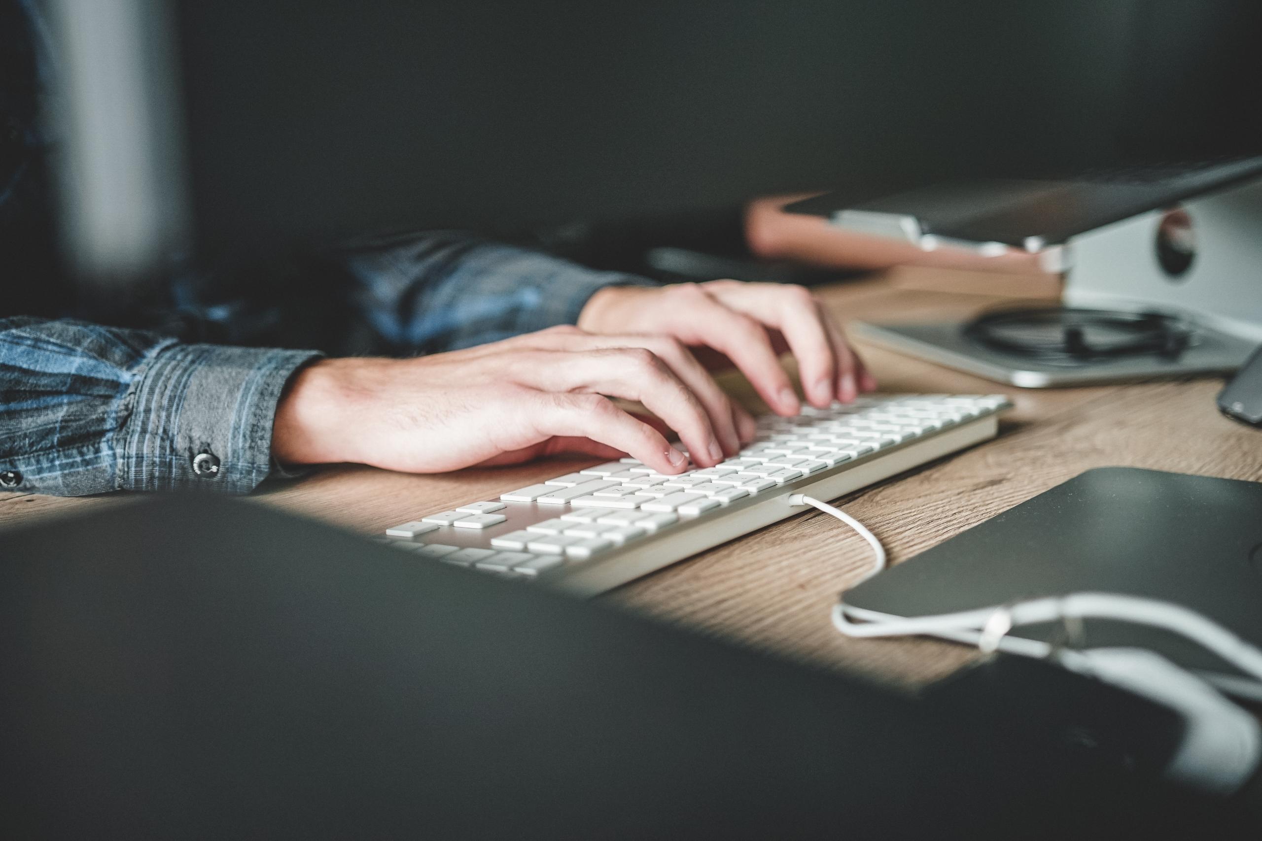 man sitting at desk typing on computer keyboard