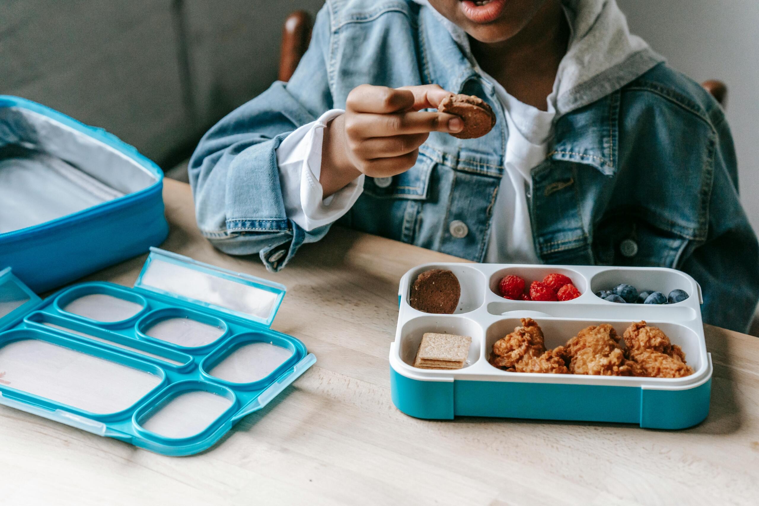learner sitting at a table at school eating lunch from a bento box