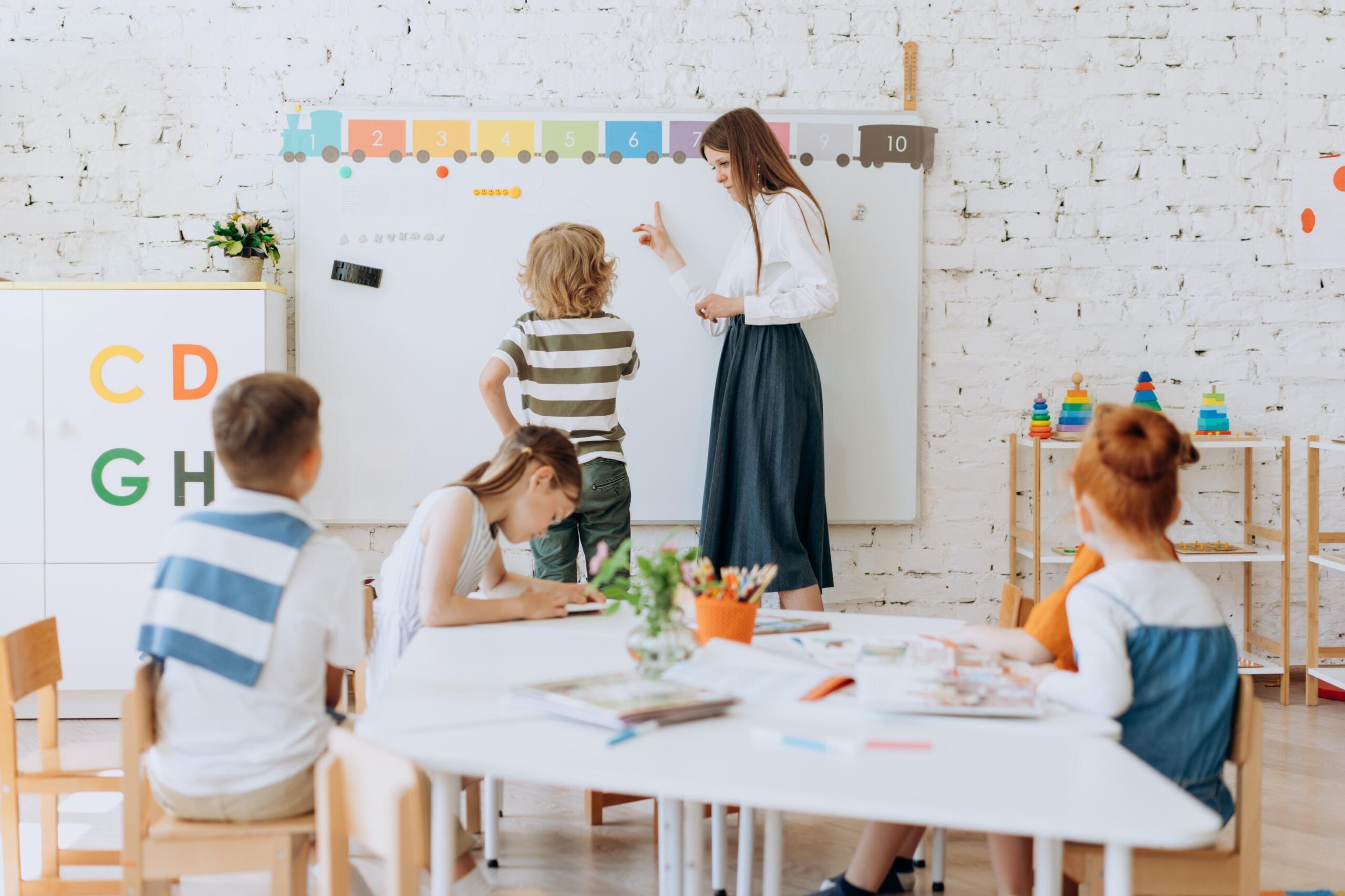 teacher helping young children earn using a number line on a whiteboard