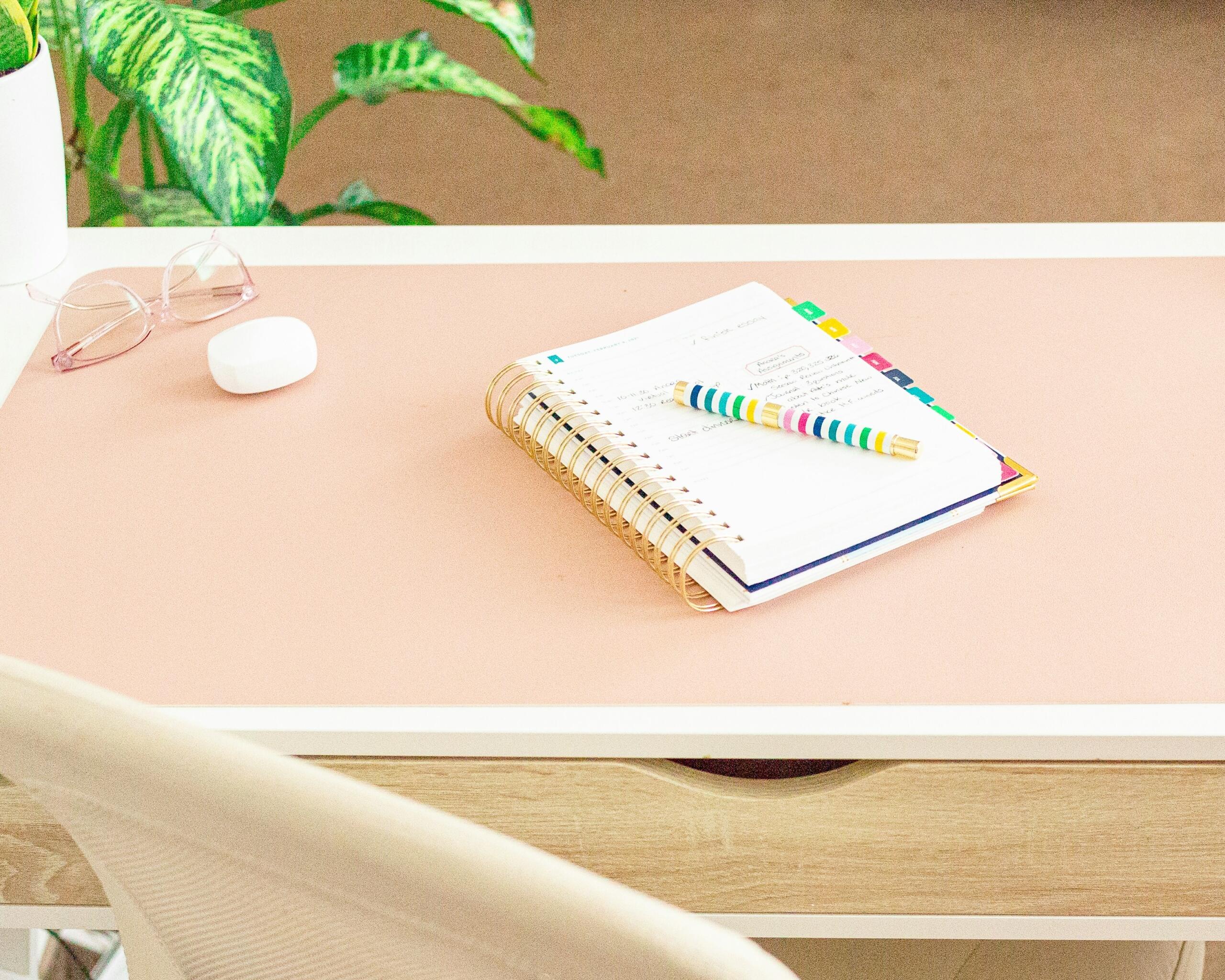 a-desk-with-a-notepad-pen-and-glasses-on-it