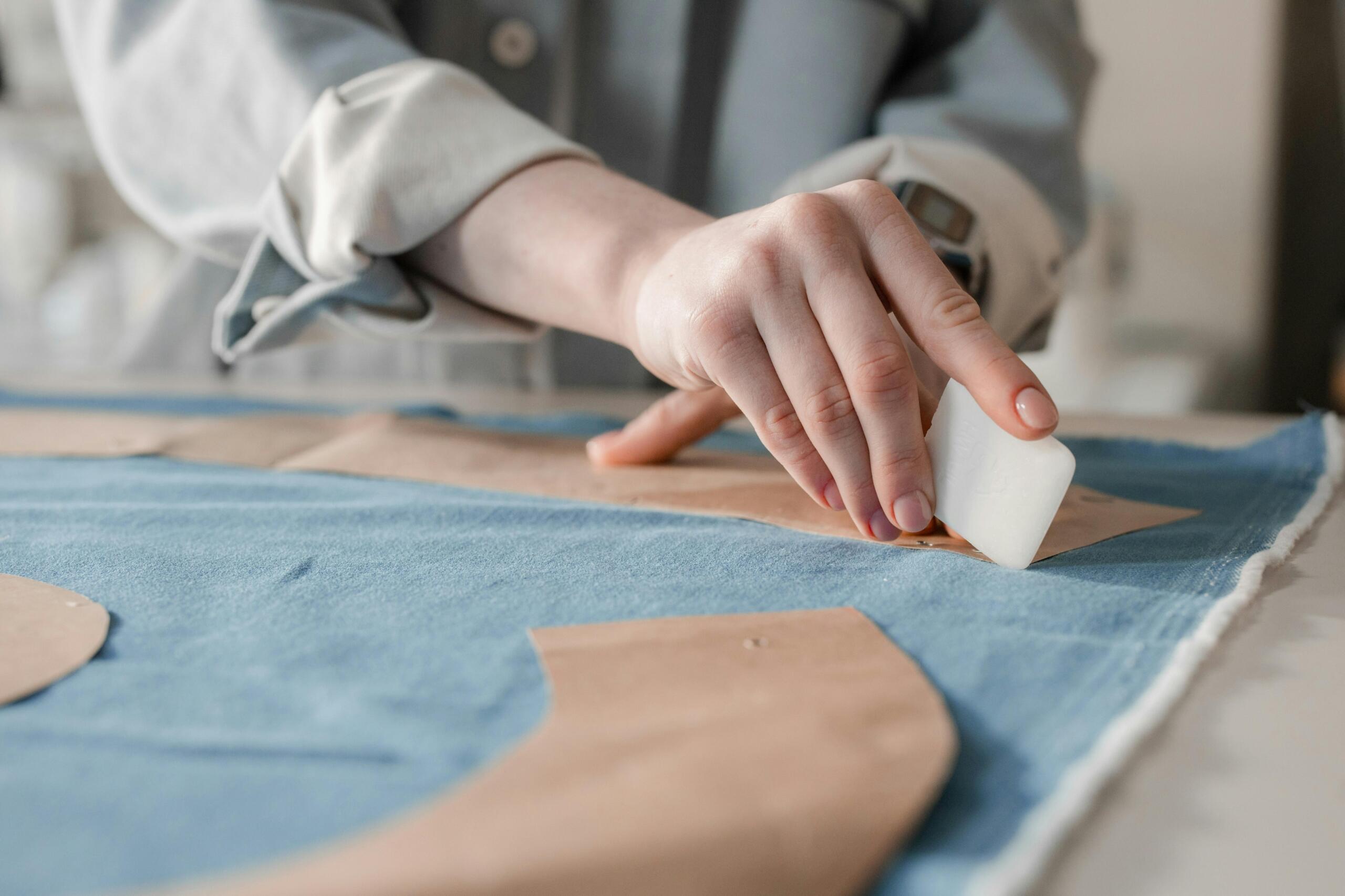 fashion designer using chalk to cut pattern onto denim fabric