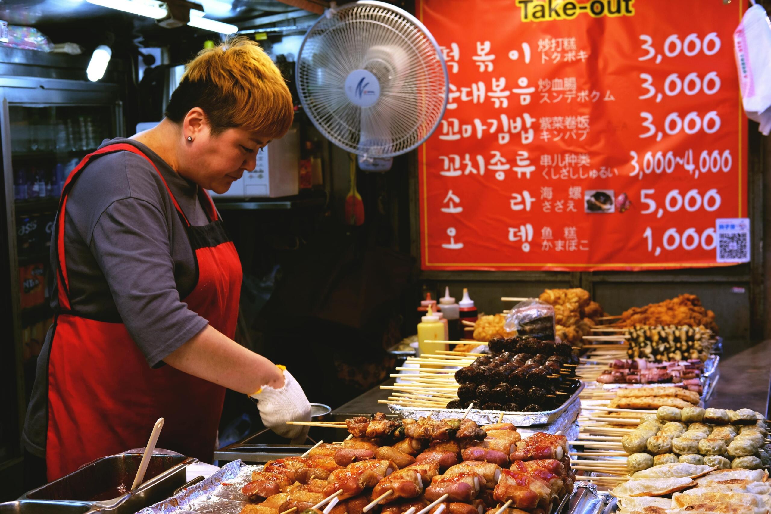 woman cooking barbecue at street food stall in korea