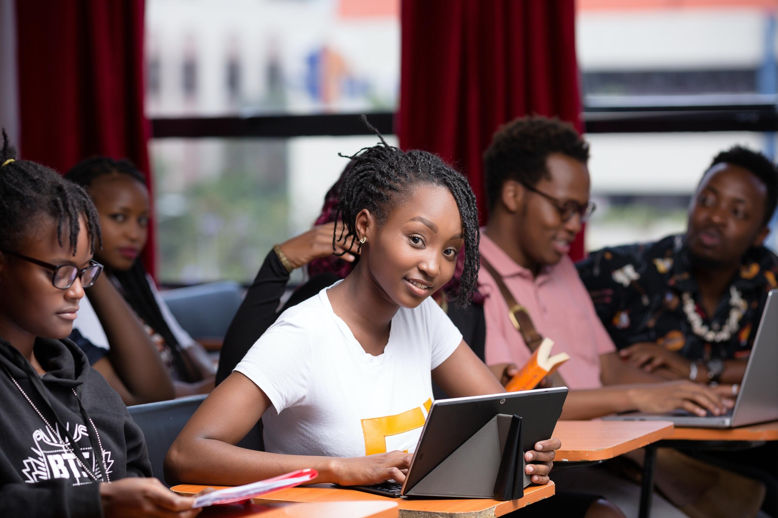 group of students sitting in class using laptops and tablets