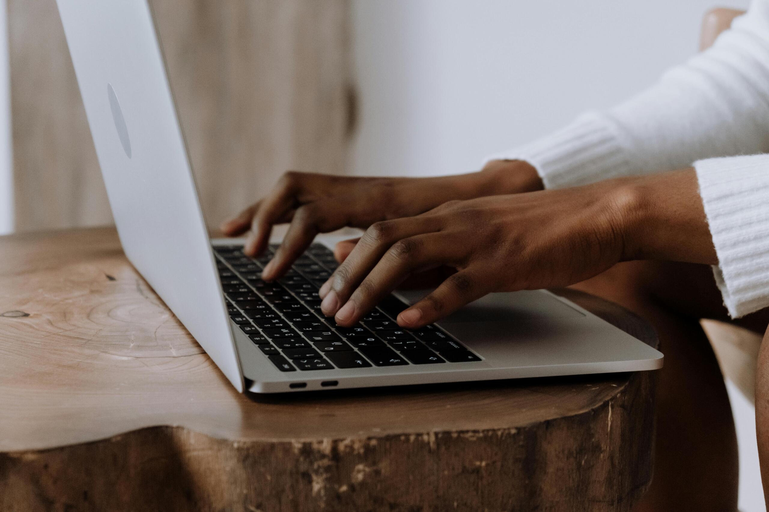 person sitting at table typing on laptop