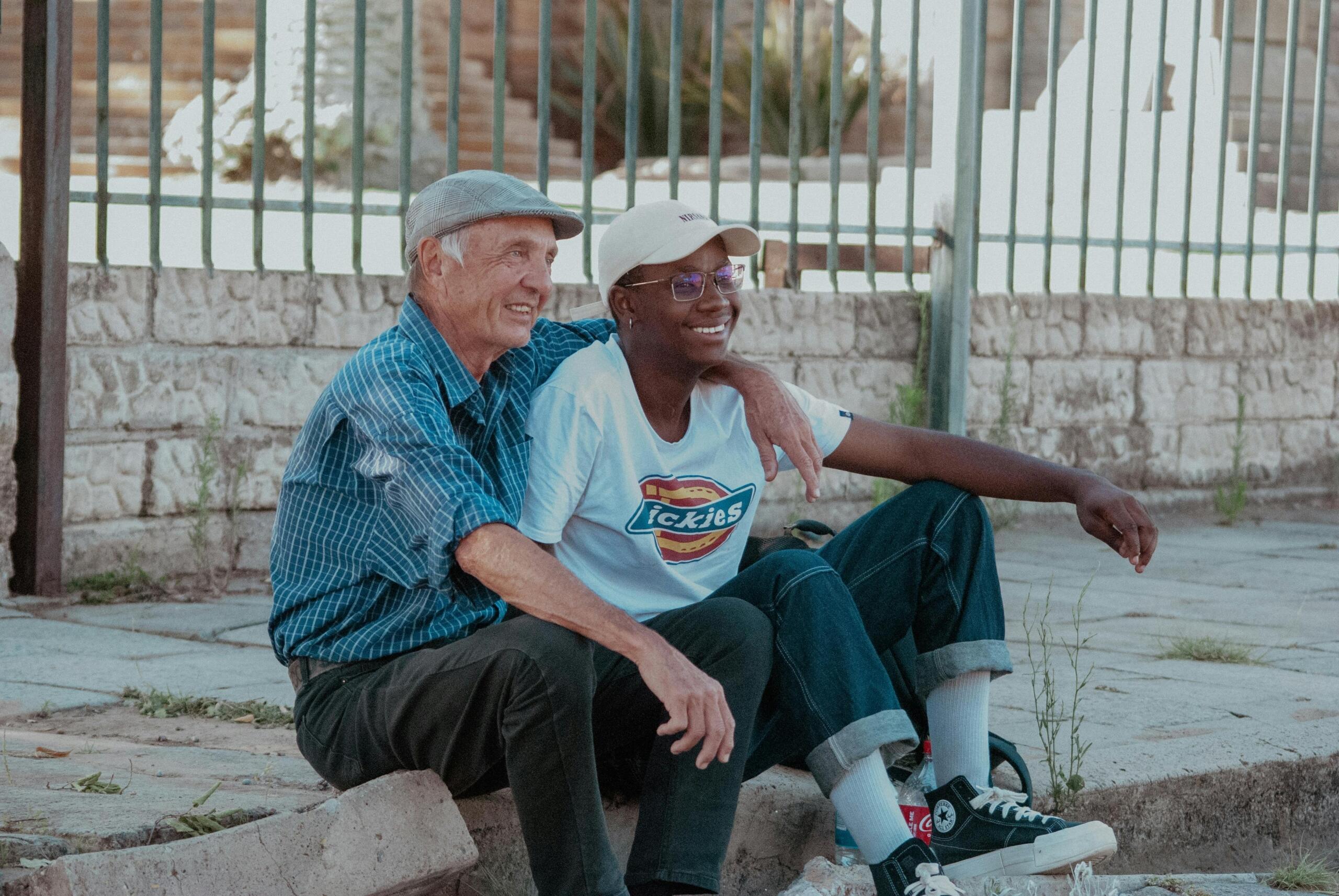 an old man sitting beside a younger man with his arm draped over his shoulder
