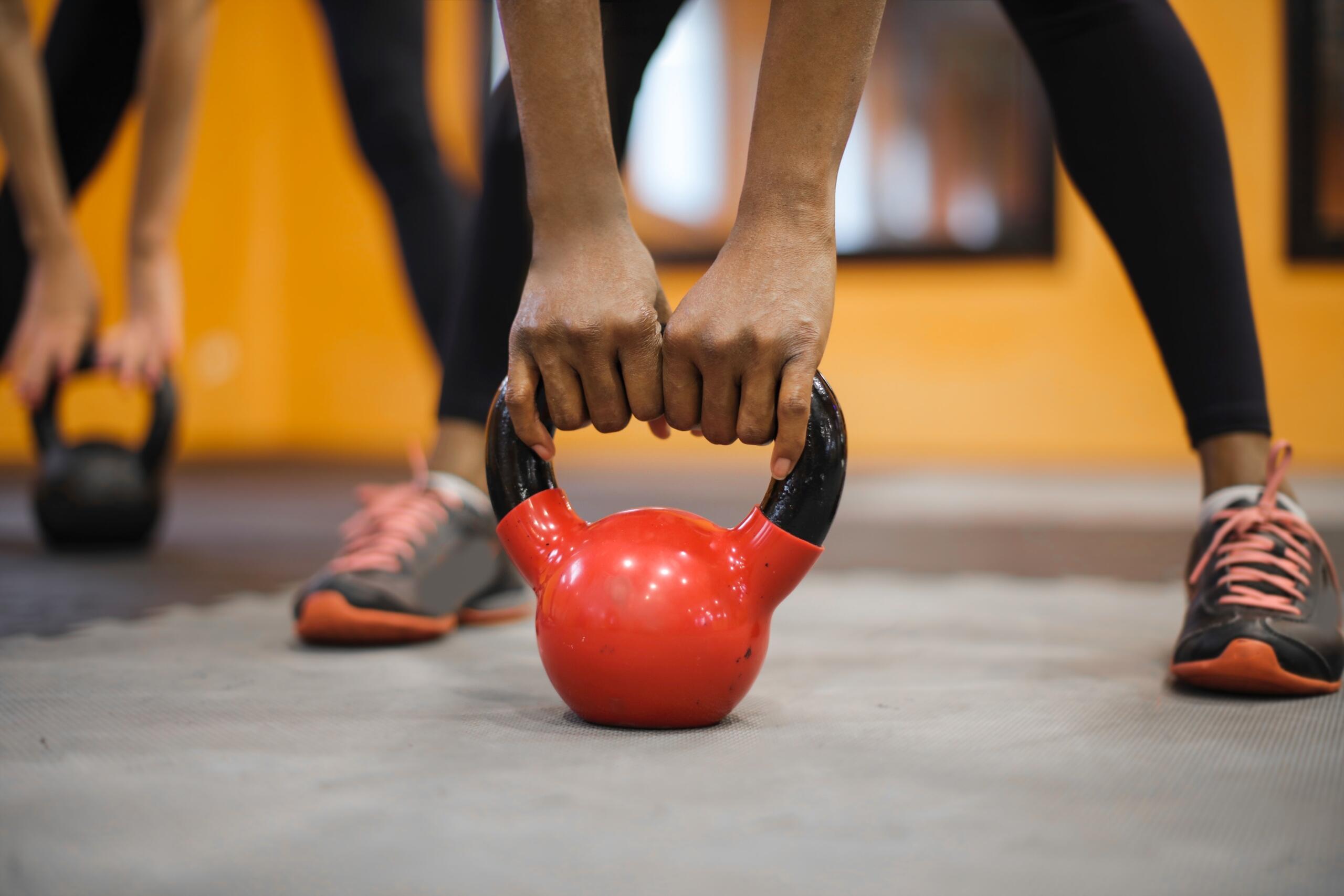 close up of people in a gym bending down to lift kettlebells