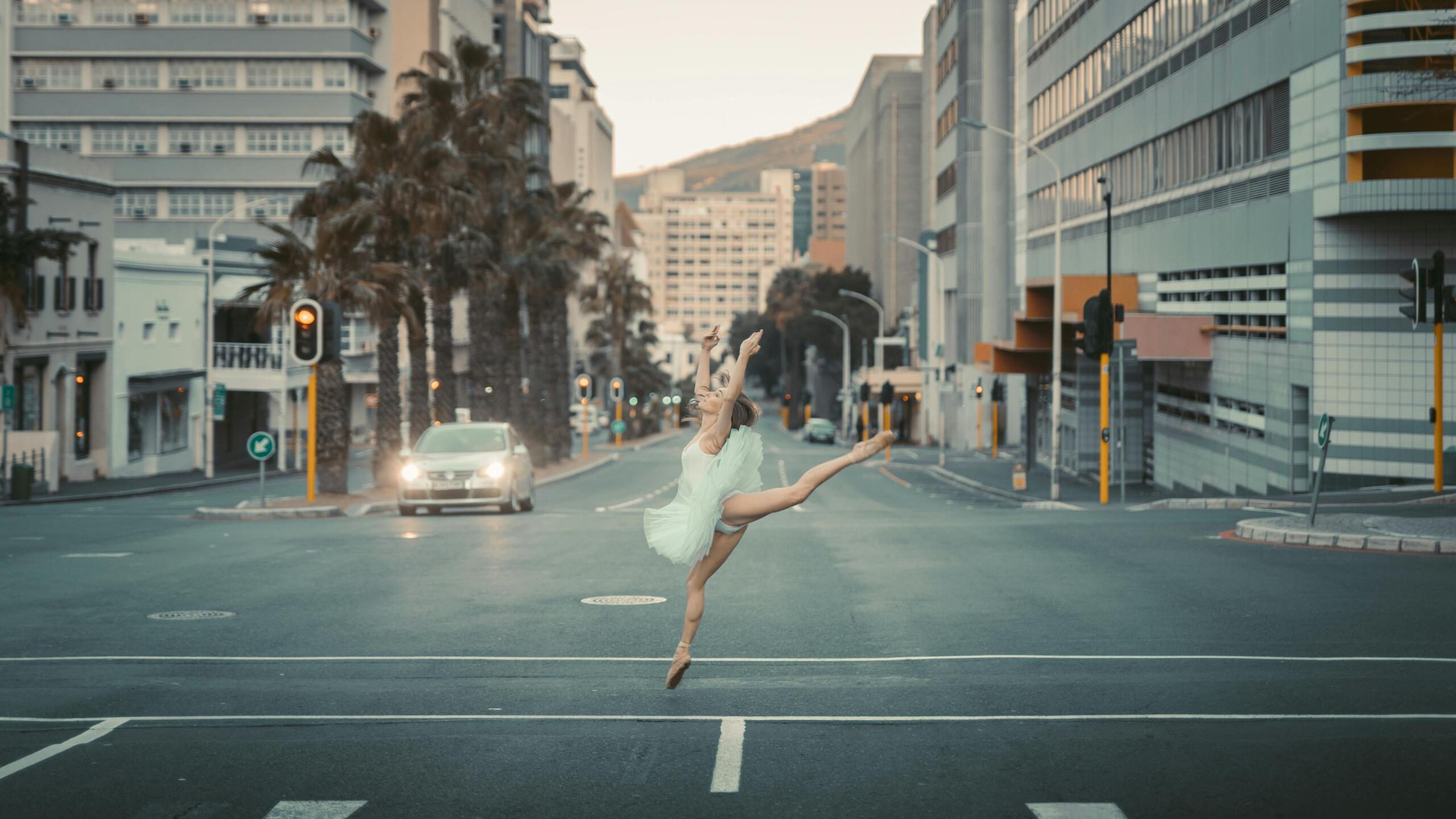 a ballerina in a white tutu jumping in the middle of an urban street