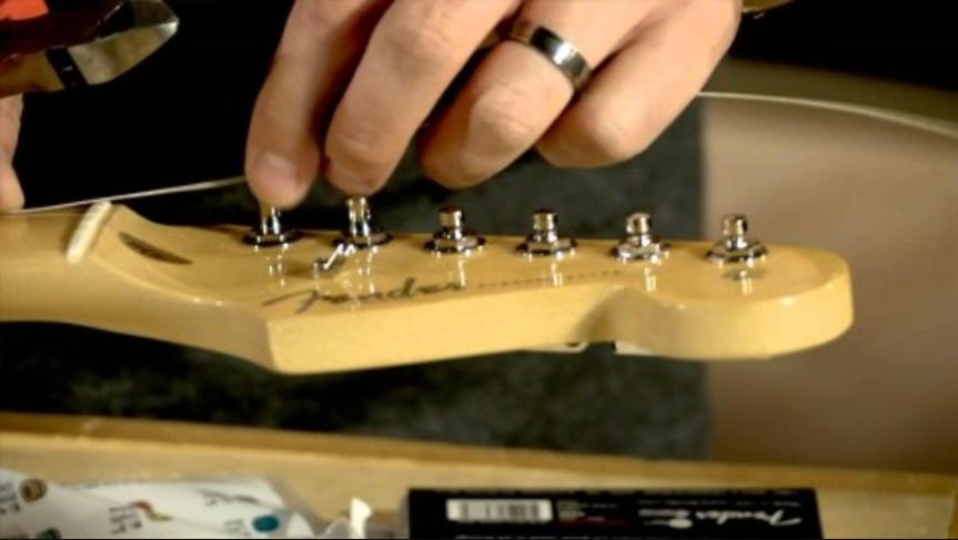 A headstock of a guitar as someone changes strings